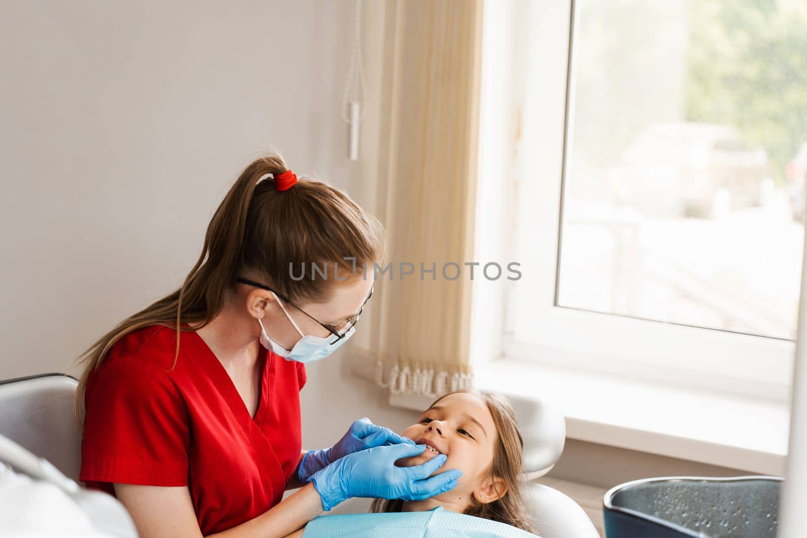 Consultation with child dentist at dentistry. Teeth treatment. Children dentist examines girl mouth and teeth and treats toothaches. Happy child patient of dentistry