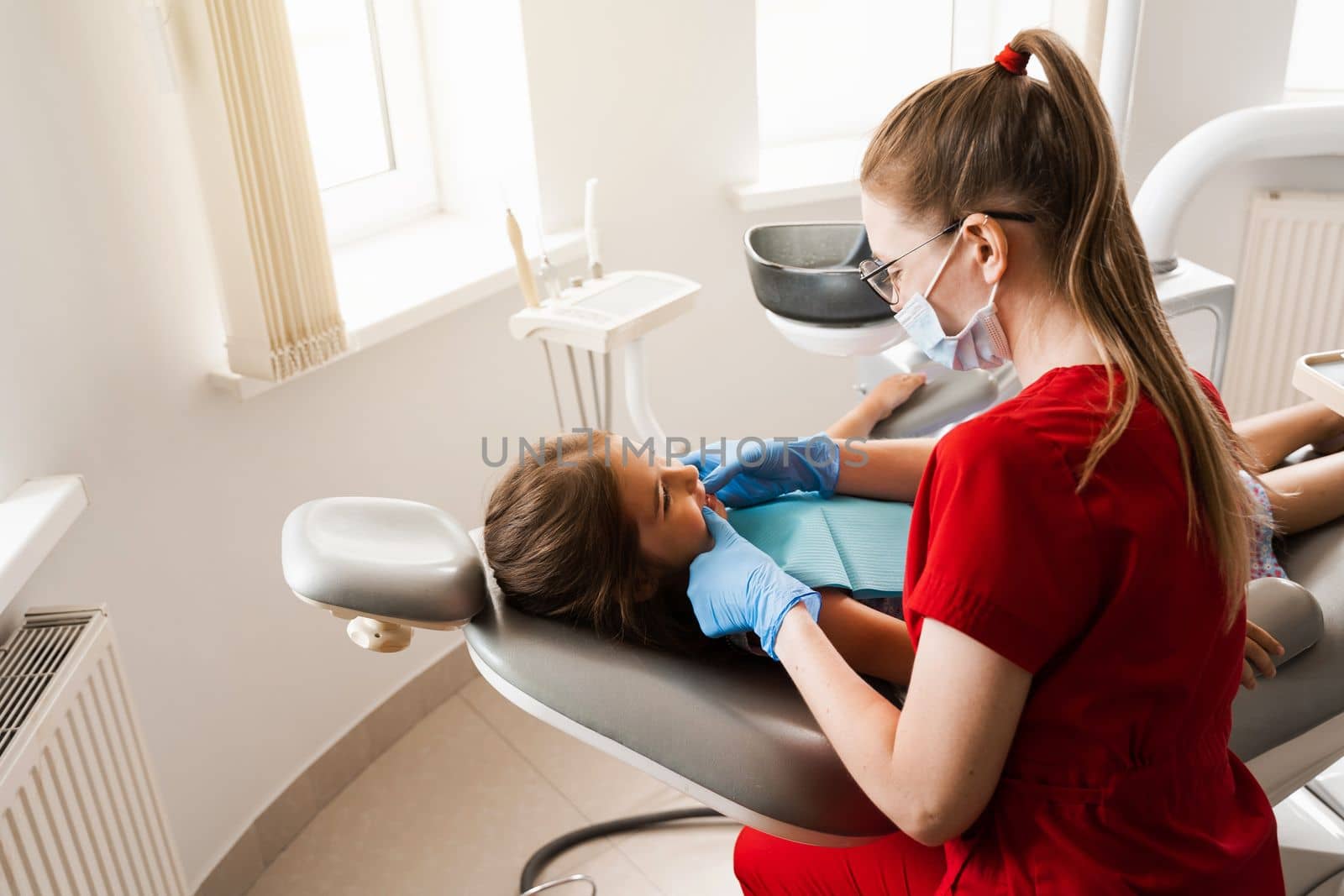 Consultation with pediatric dentist in dentistry. Pediatric dentist examines teeth of child girl for treatment of toothache. Pain in teeth in children. by Rabizo