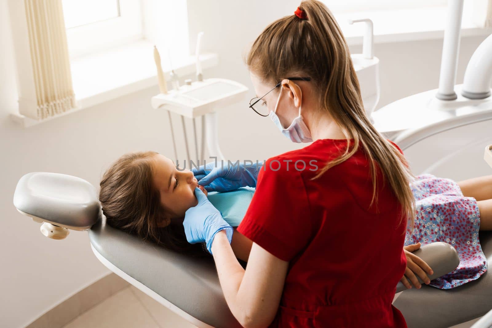 Consultation with pediatric dentist in dentistry. Pediatric dentist examines teeth of child girl for treatment of toothache. Pain in teeth in children