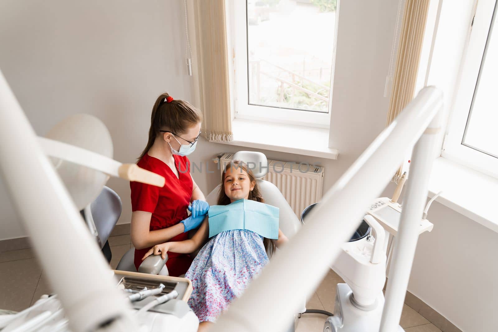 Pediatric dentist and cheerful girl child smiling in dentistry. The child smiles at the consultation with the dentist