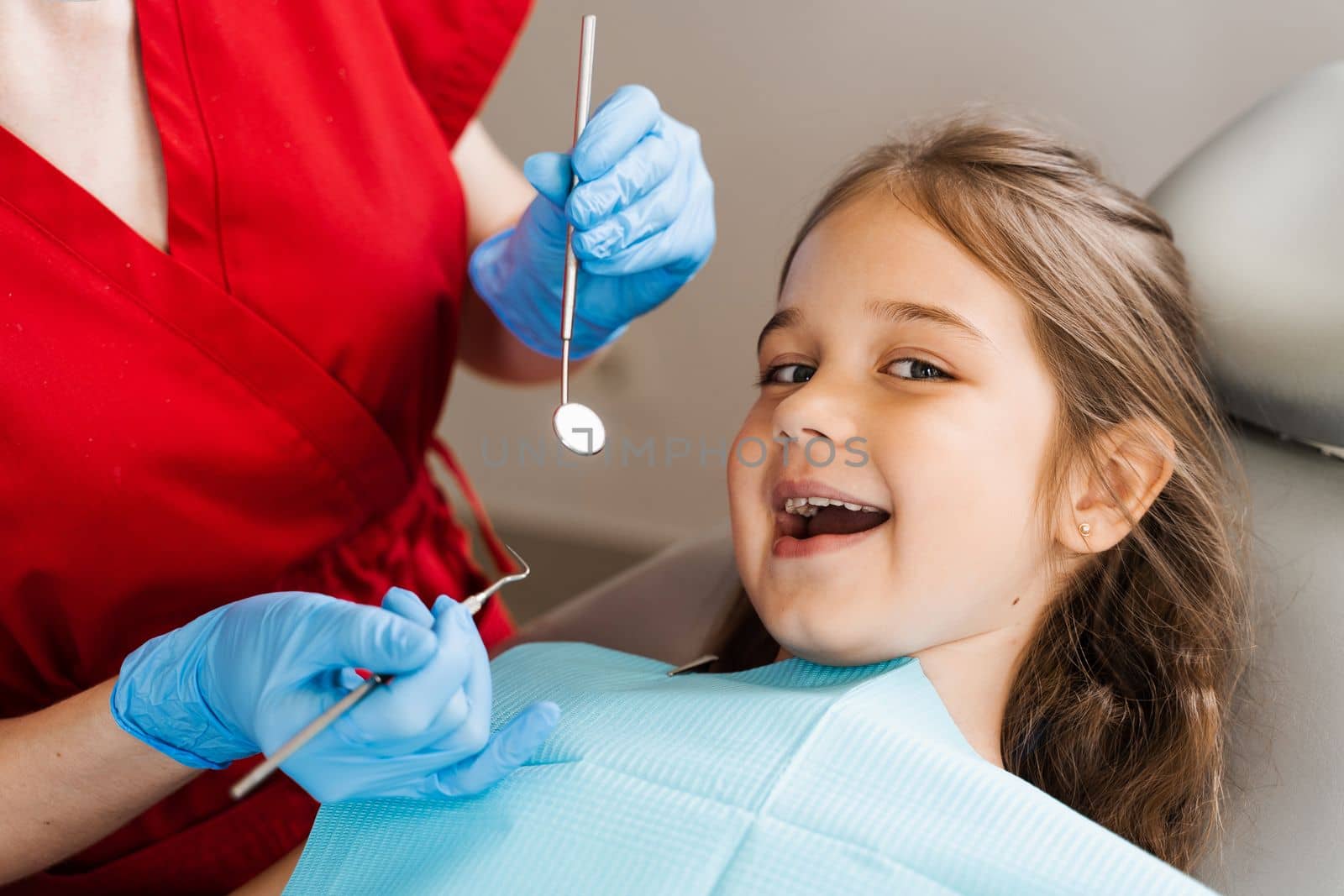 Cheerful child girl smiling at dentists consultation in dentistry. Dental diseases. Consultation with pediatric dentist for treatment of toothache in child. by Rabizo