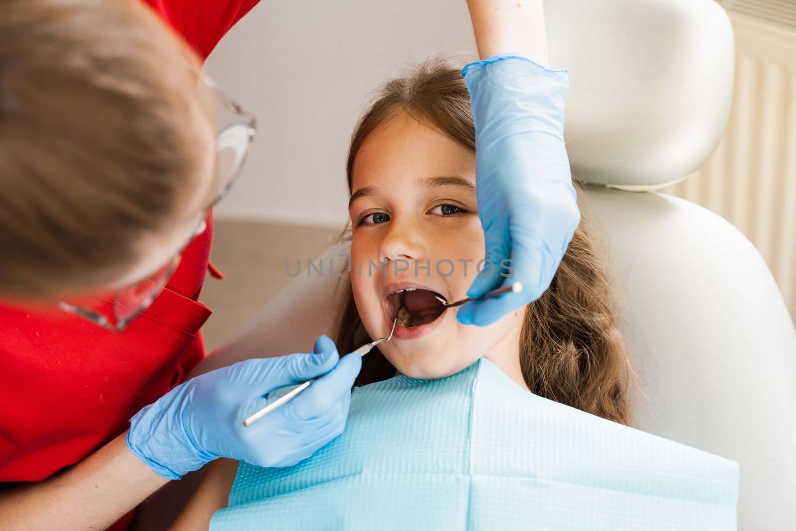 Cheerful child girl smiling at dentists consultation in dentistry. Dental diseases. Consultation with pediatric dentist for treatment of toothache in child. by Rabizo