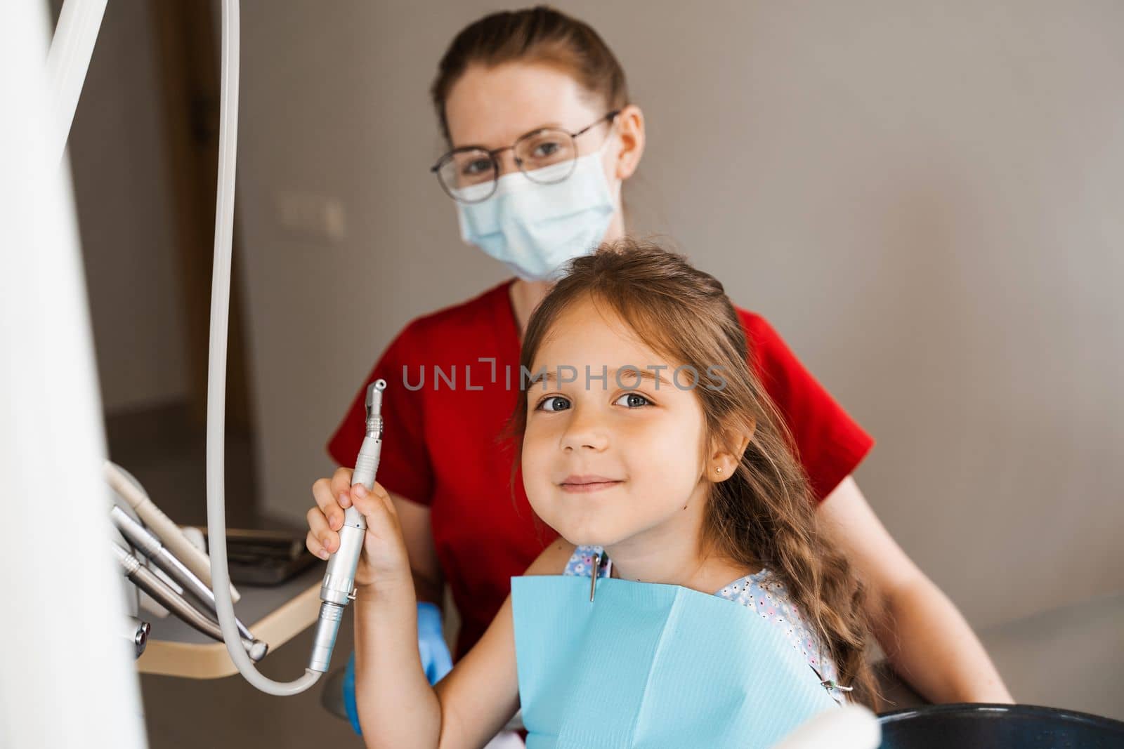 Cheerful girl child holding dental drill and smiling in dentistry. The child smiles at the consultation with the dentist