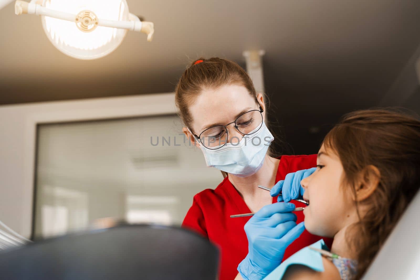 Consultation with pediatric dentist at dentistry. Teeth treatment. Children dentist examines girl mouth and teeth and treats toothaches. Happy child patient of dentistry