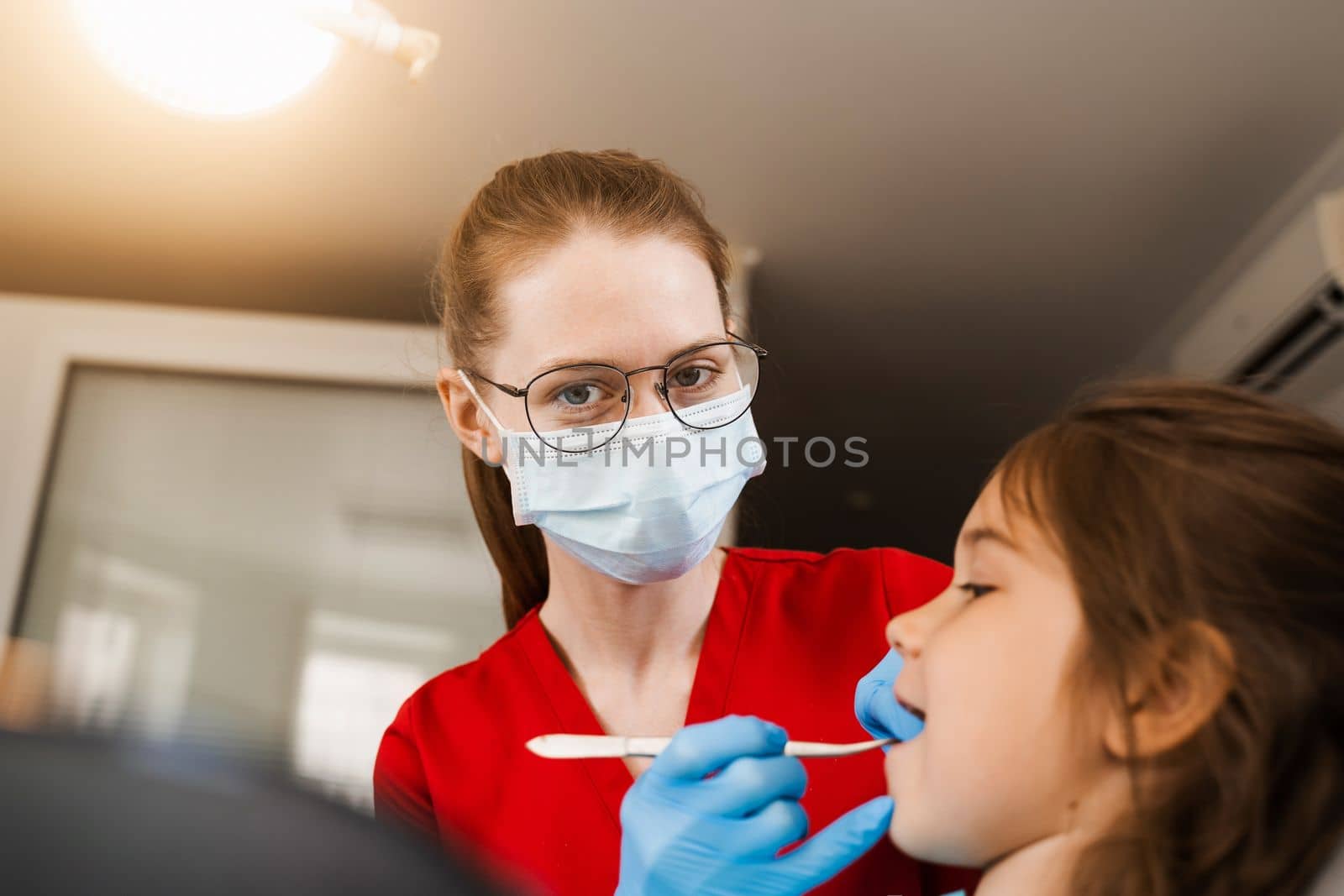 Consultation with pediatric dentist at dentistry. Teeth treatment. Children dentist examines girl mouth and teeth and treats toothaches. Happy child patient of dentistry