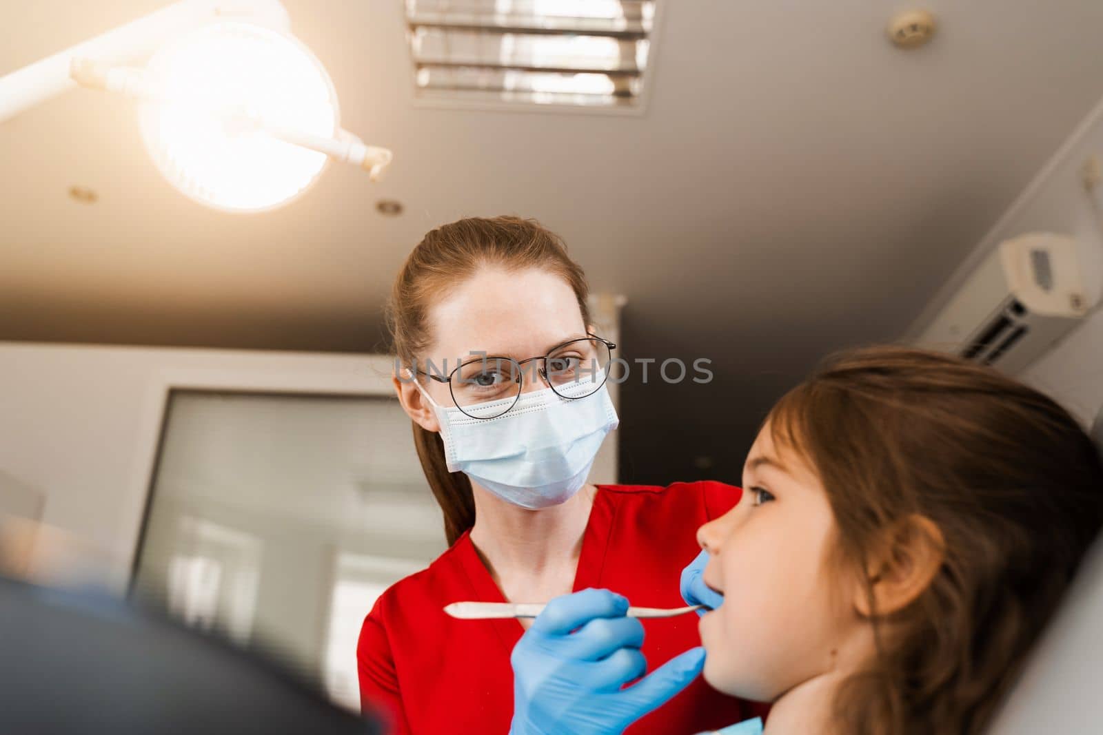 Consultation with pediatric dentist at dentistry. Teeth treatment. Children dentist examines girl mouth and teeth and treats toothaches. Happy child patient of dentistry. by Rabizo