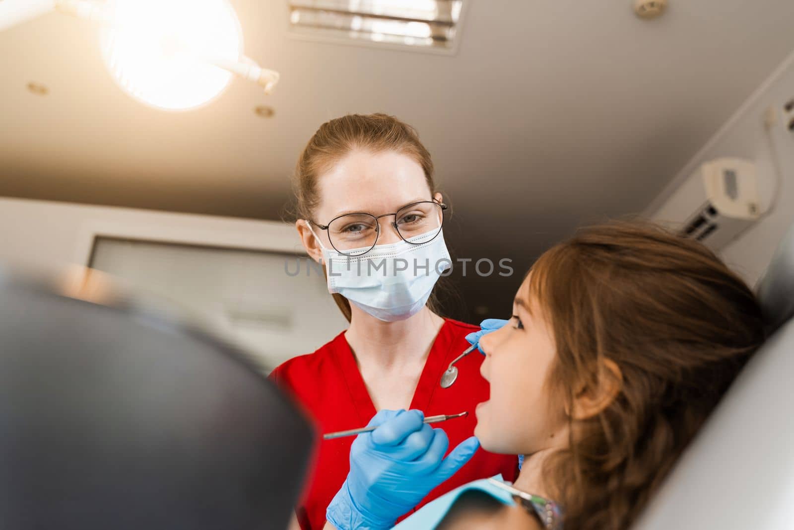 Pediatric dentist and cheerful girl child smiling in dentistry. The child smiles at the consultation with the dentist