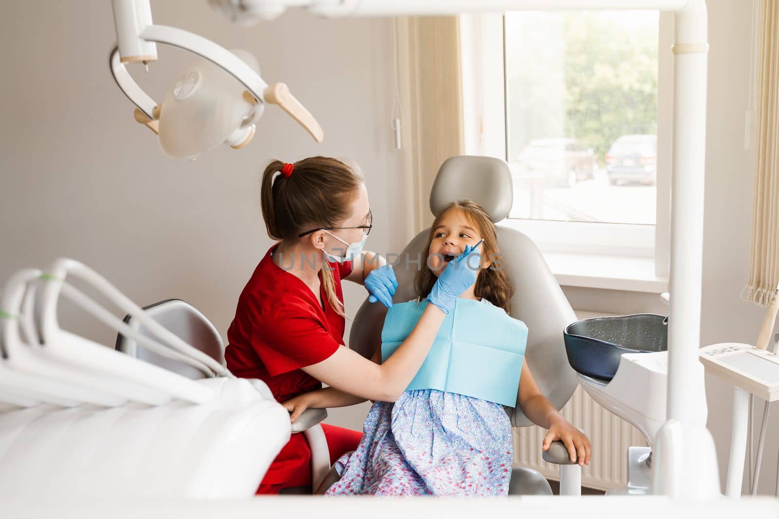 Pediatric dentist examines teeth of child girl for treatment of toothache. Pain in teeth in children. Consultation with pediatric dentist in dentistry. by Rabizo