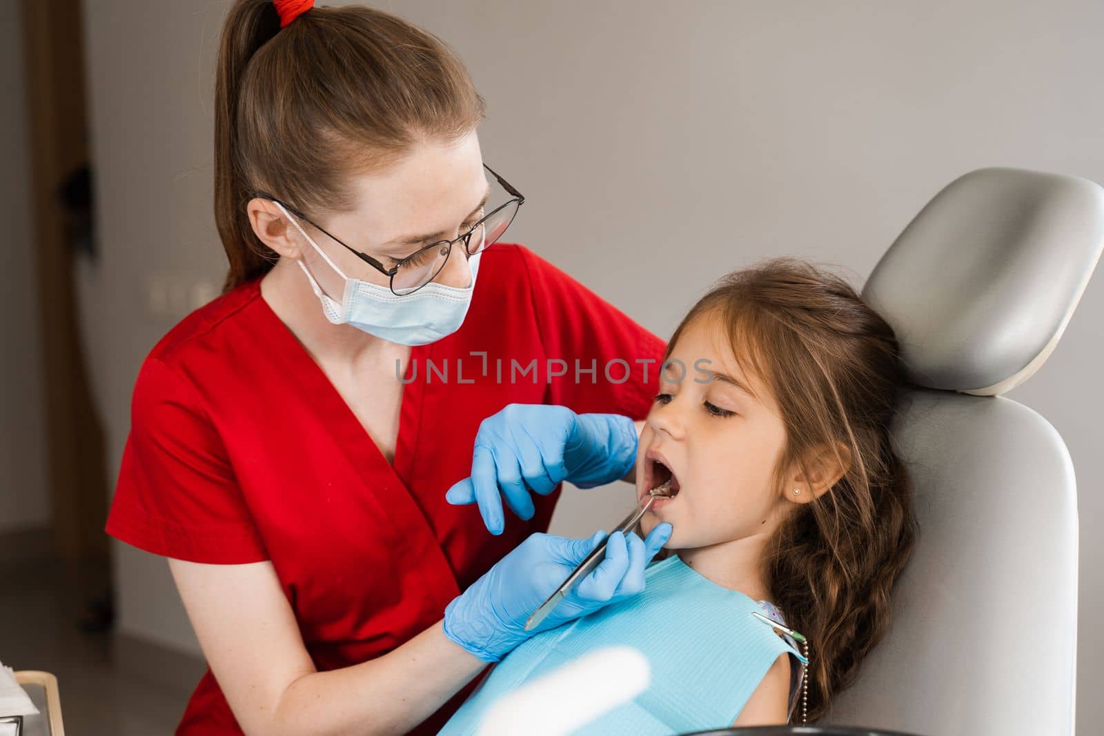 Pediatric dentist examines child girl mouth and teeth and treats toothaches. Happy child patient of dentistry. Consultation with child dentist at dentistry. Teeth treatment