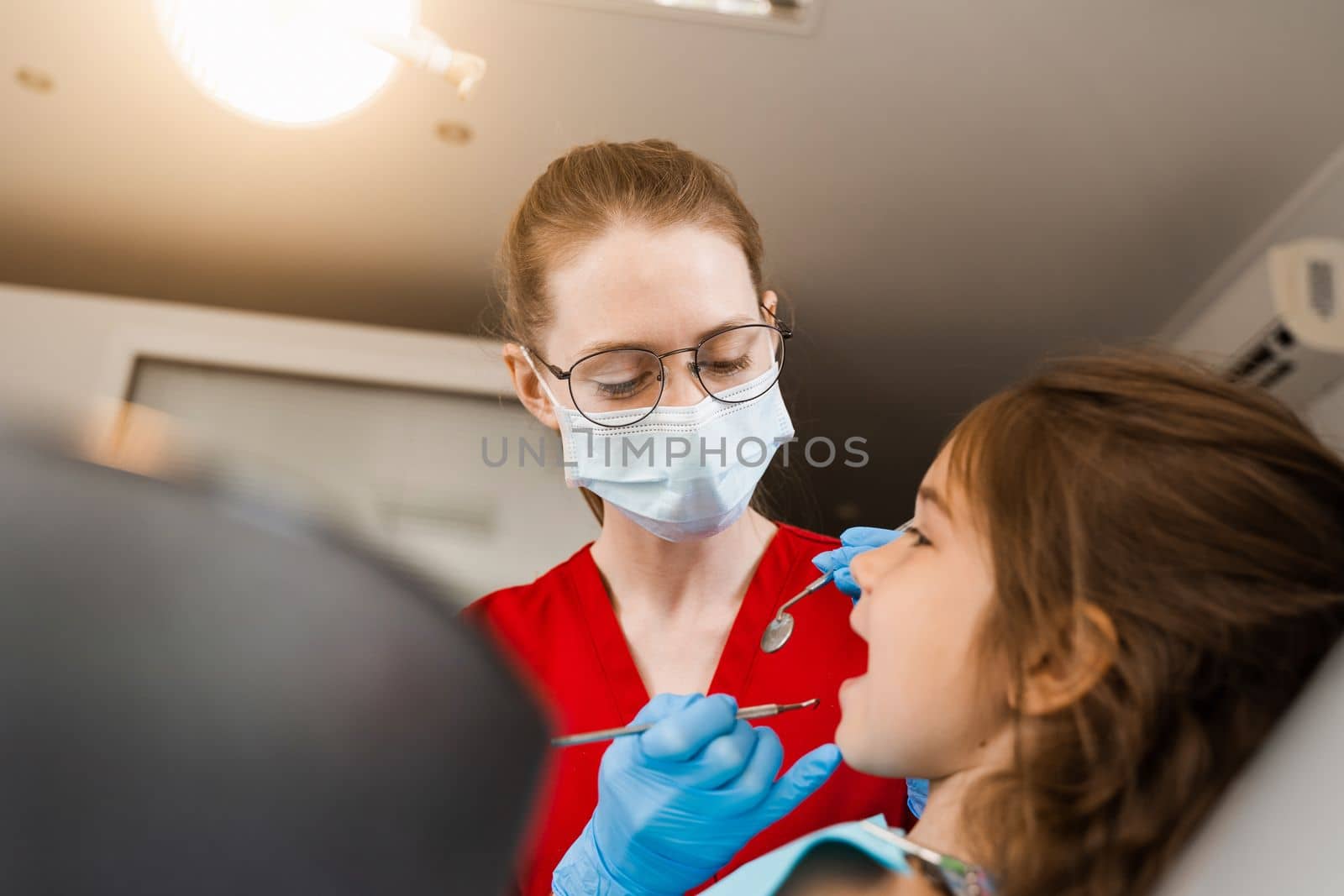 Pediatric dentist and cheerful girl child smiling in dentistry. The child smiles at the consultation with the dentist