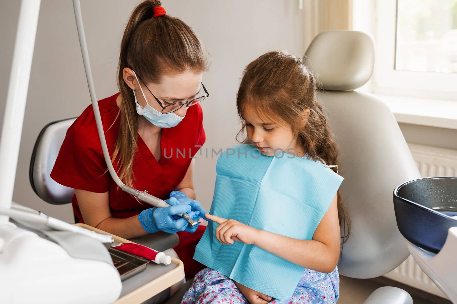 Professional hygiene for teeth of child in dentistry. Professional teeth cleaning for child girl. Pediatric dentist examines and consults kid patient in dentistry