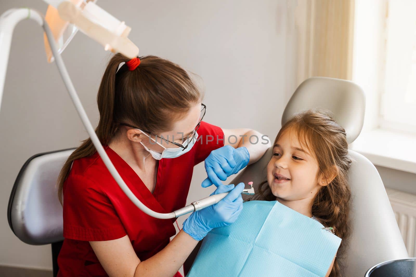 Professional hygiene for teeth of child in dentistry. Professional teeth cleaning for child girl. Pediatric dentist examines and consults kid patient in dentistry. by Rabizo