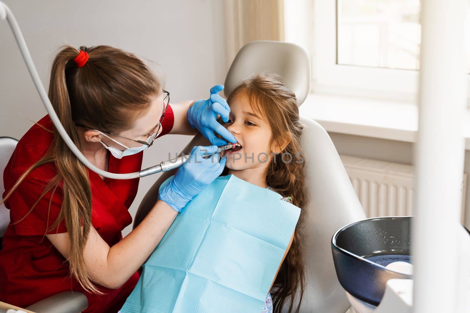 Child dentist makes professional teeth cleaning in dentistry. Professional hygiene for teeth of child in dentistry. Pediatric dentist examines and consults kid patient in dentistry