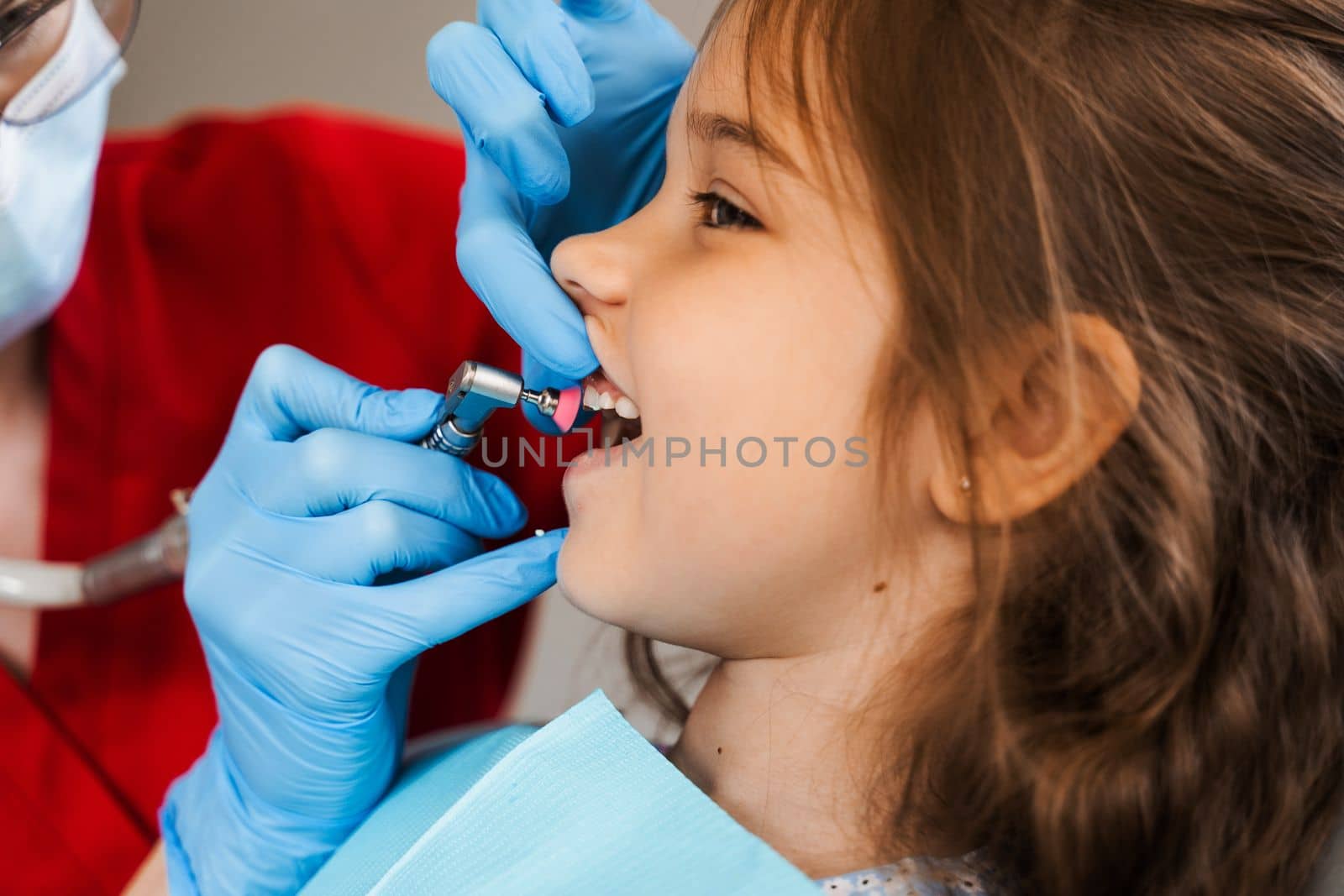 Child dentist makes professional teeth cleaning in dentistry. Professional hygiene for teeth of child in dentistry. Pediatric dentist examines and consults kid patient in dentistry