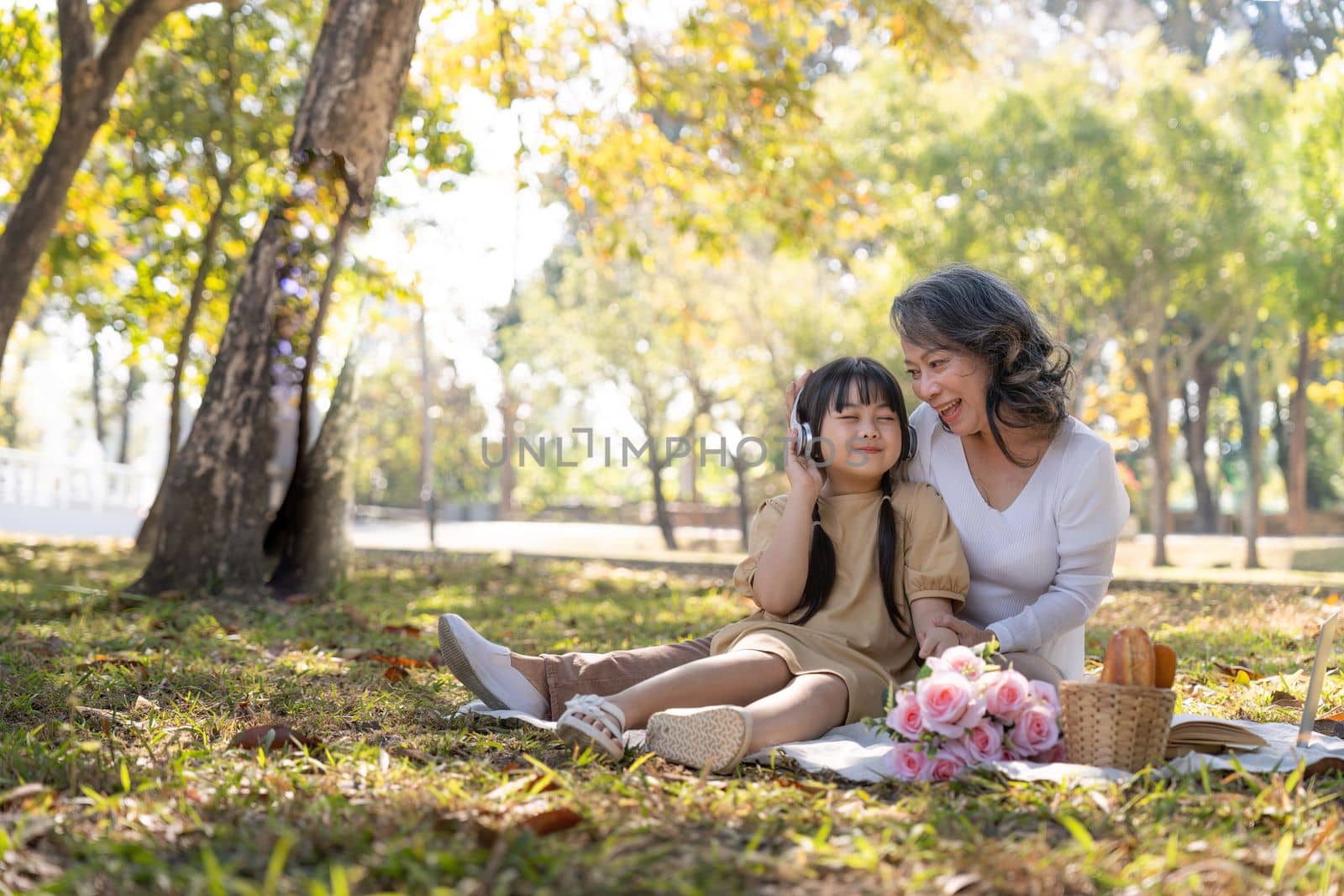 Happy Asian grandmother picnicking with her lovely granddaughter in park together. leisure and family concept by nateemee