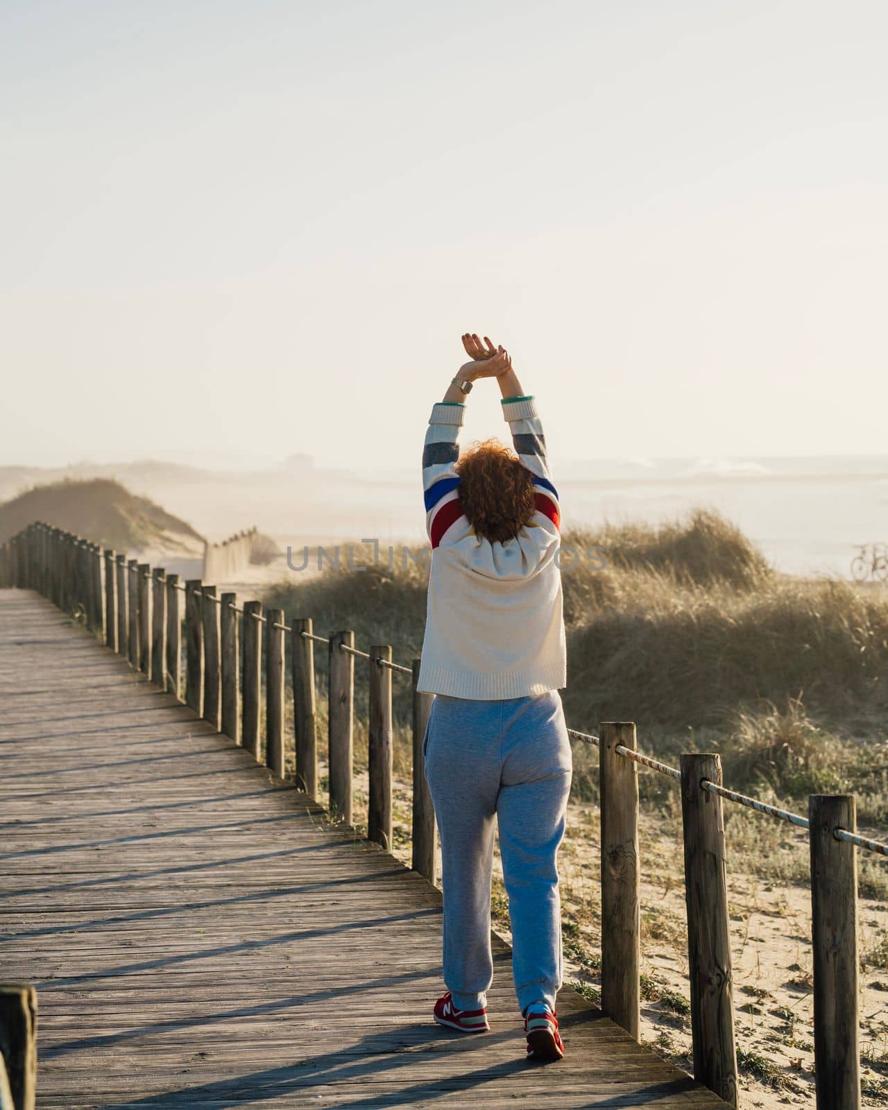 Mature woman exercise in morning, Adult female stretching muscle against beach dunes, warm up. Active lifestyle concept.