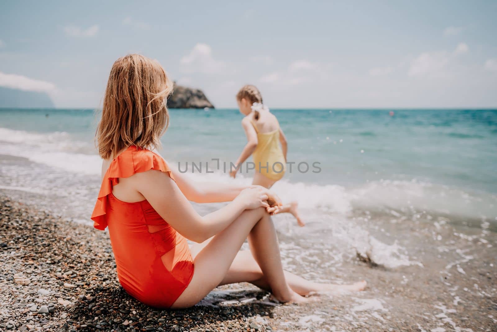 Happy loving family mother and daughter having fun together on the beach. Mum playing with her kid in holiday vacation next to the ocean - Family lifestyle and love concept by panophotograph