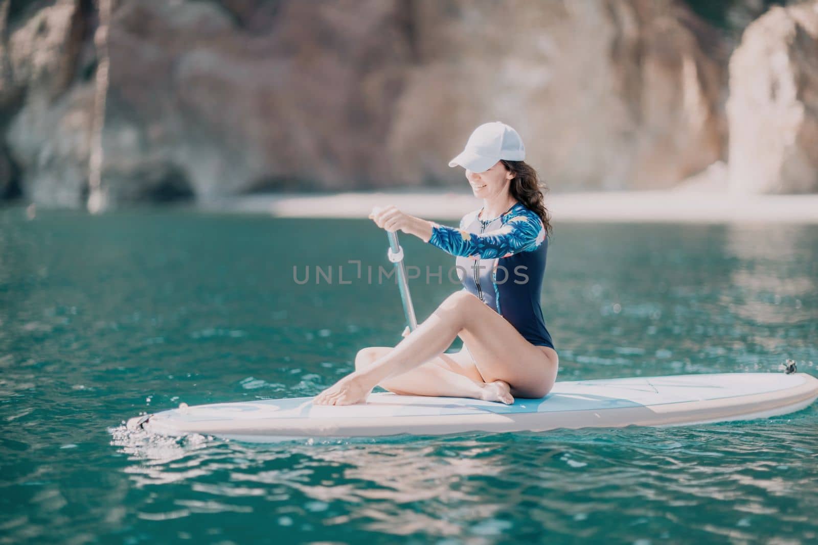 Woman sup yoga. Middle age sporty woman practising yoga pilates on paddle sup surfboard. Female stretching doing workout on sea water. Modern individual hipster outdoor summer sport activity