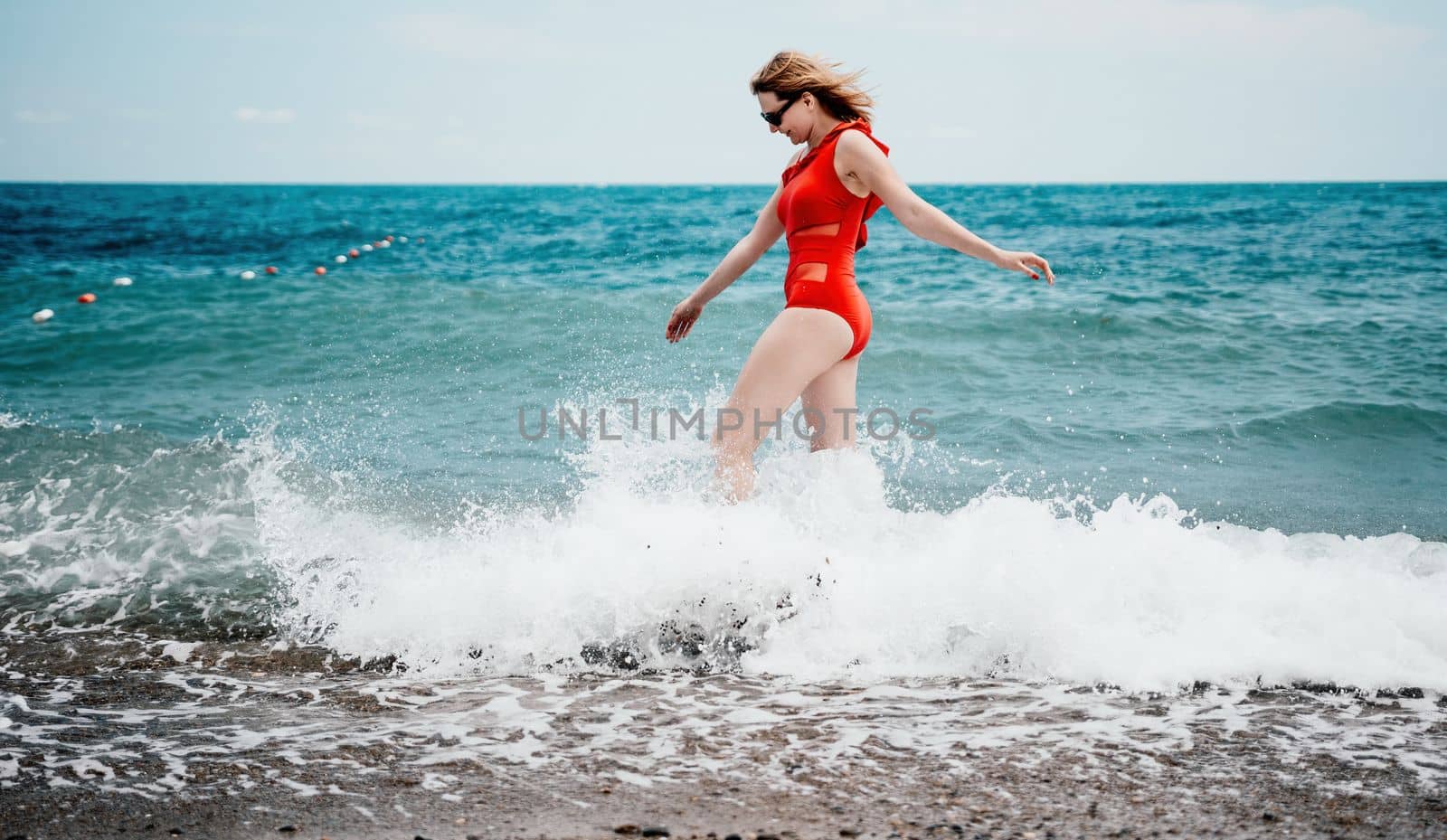 Young happy woman walks carefree on the seaside. Happy lady in red bikini. Portrait beautiful young woman relax smile around beach sea ocean in holiday vacation travel trip.
