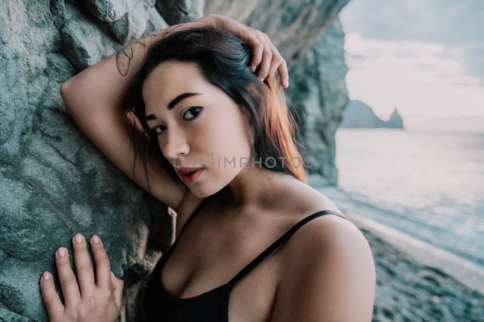 Portrait of cheerful female climber ascending a rock. The athlete girl trains in nature. Woman overcomes difficult climbing route.