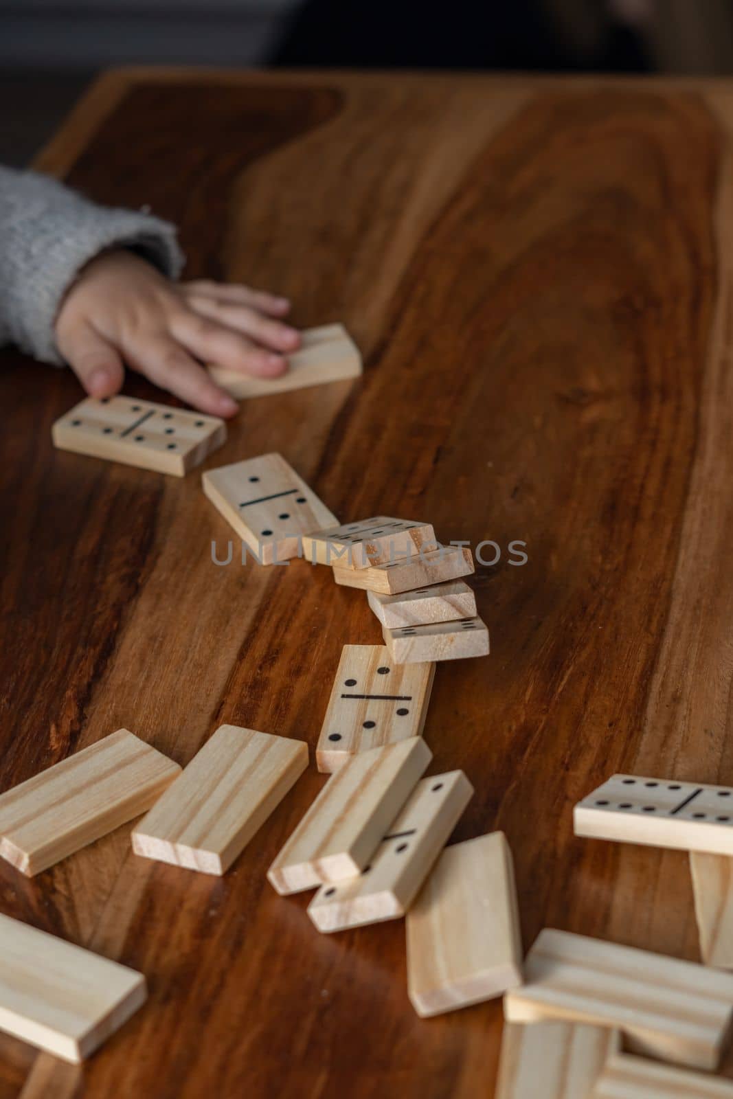 child's hands in gray sweater playing dominoes with blurred focus