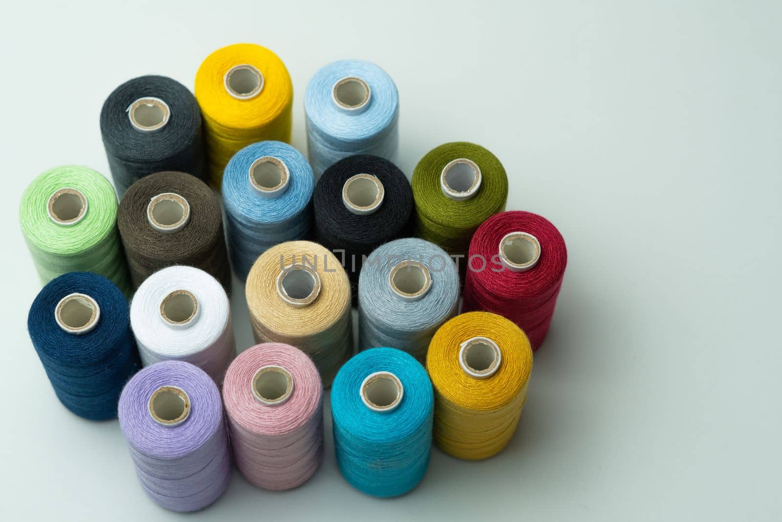 spools of colored sewing thread on white background with copy space