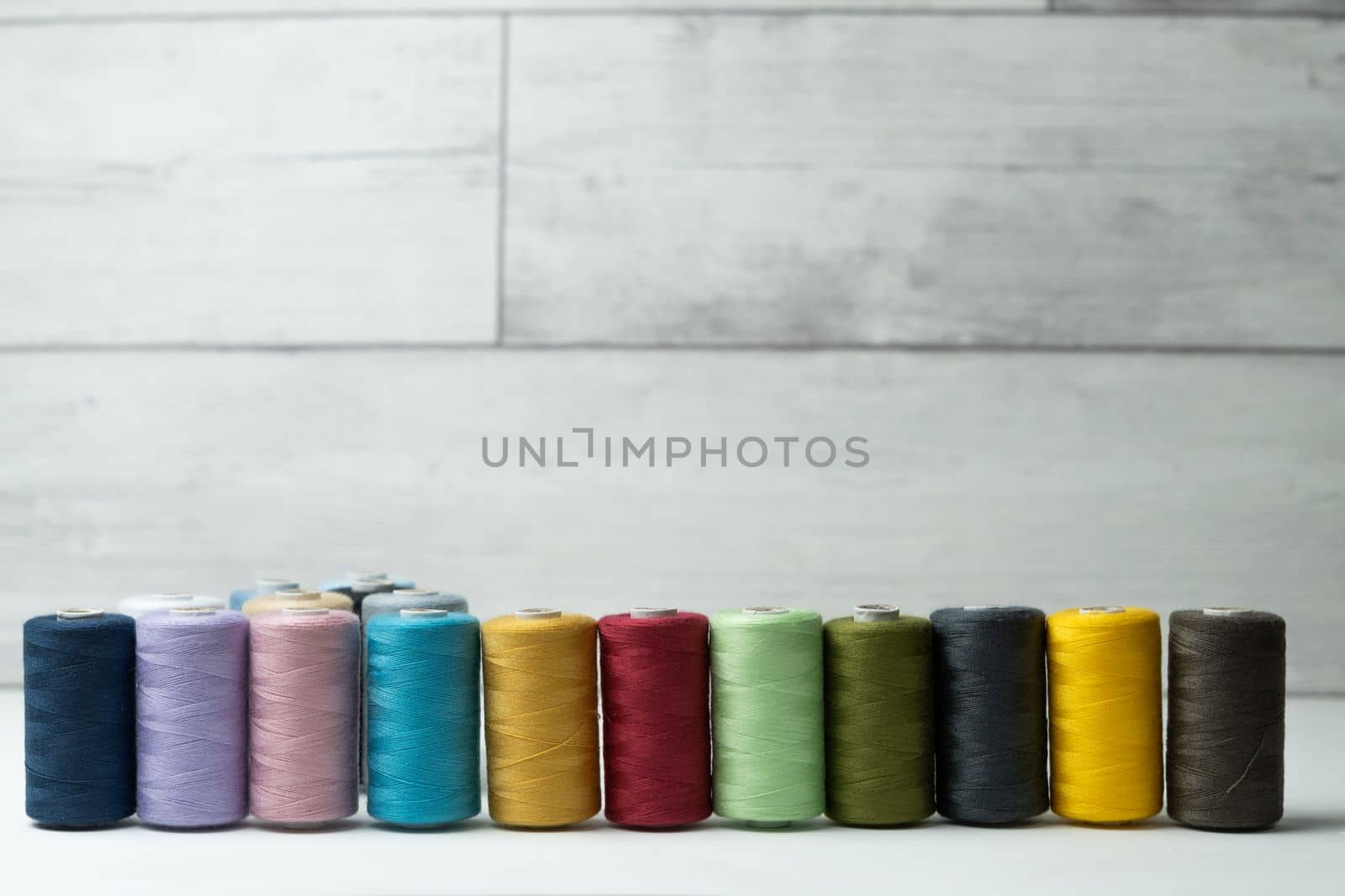 spools of colored sewing thread on white background with copy space