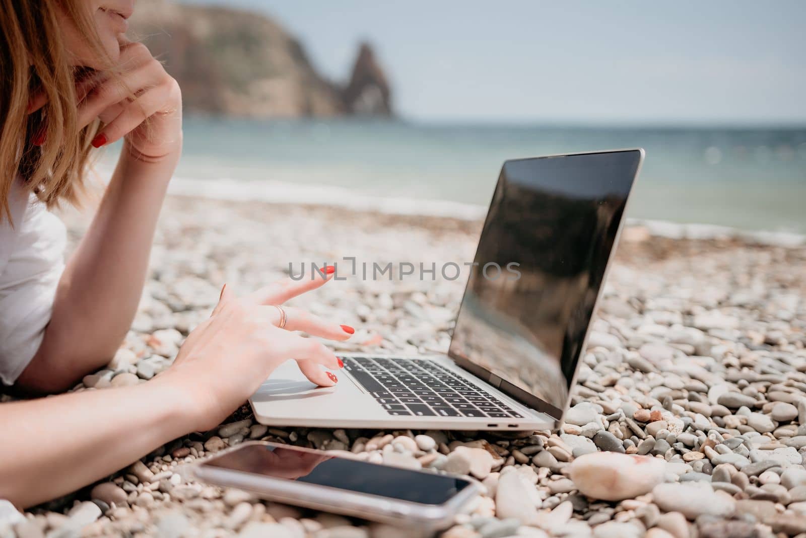 Woman sea laptop. Business woman in yellow hat working on laptop by sea. Close up on hands of pretty lady typing on computer outdoors summer day. Freelance, digital nomad, travel and holidays concept. by panophotograph