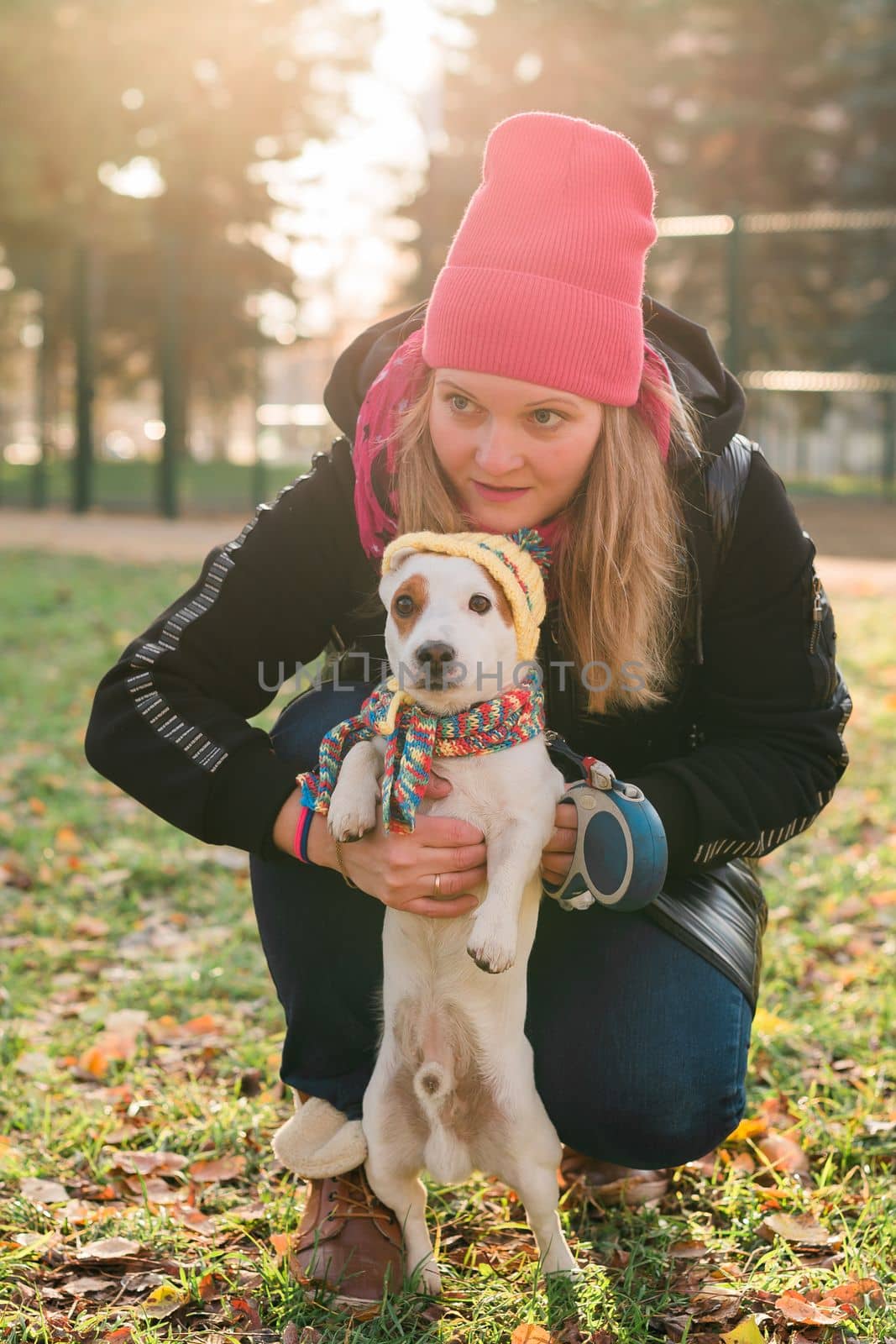 Woman pet owner walking dog jack russell terrier in funny clothes on street outdoors. Pet care concept by Satura86