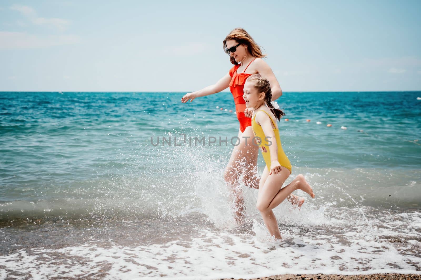 Happy loving family mother and daughter having fun together on the beach. Mum playing with her kid in holiday vacation next to the ocean - Family lifestyle and love concept by panophotograph