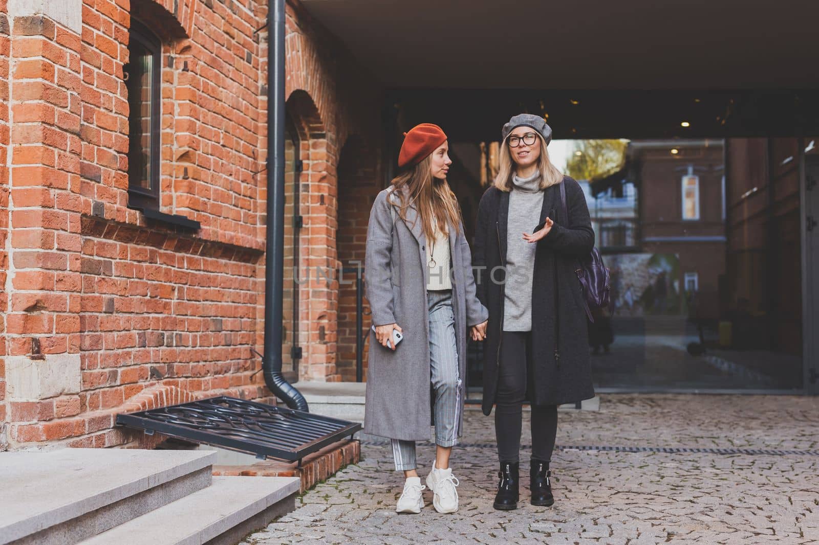 Young pretty girls friends having fun outdoor in autumn evening in city laughing and going crazy on the street - friendship and funny people