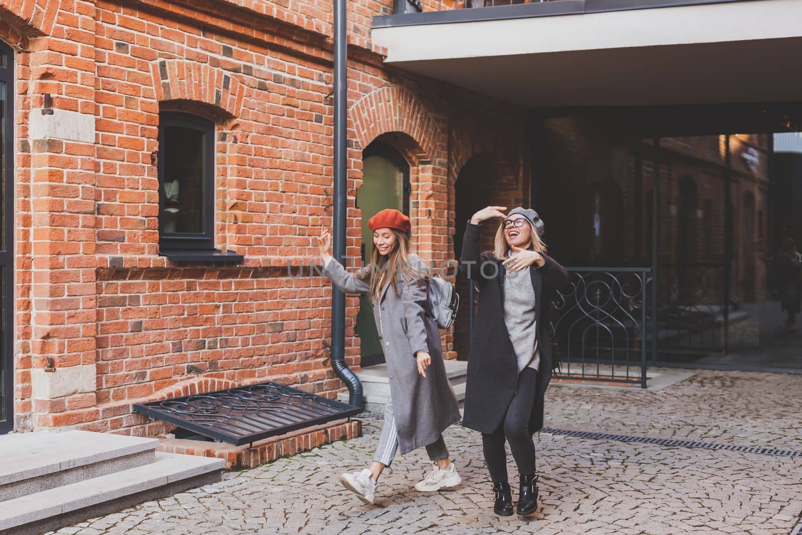 Young pretty girls friends having fun outdoor in autumn evening in city laughing and going crazy on the street - friendship and funny people