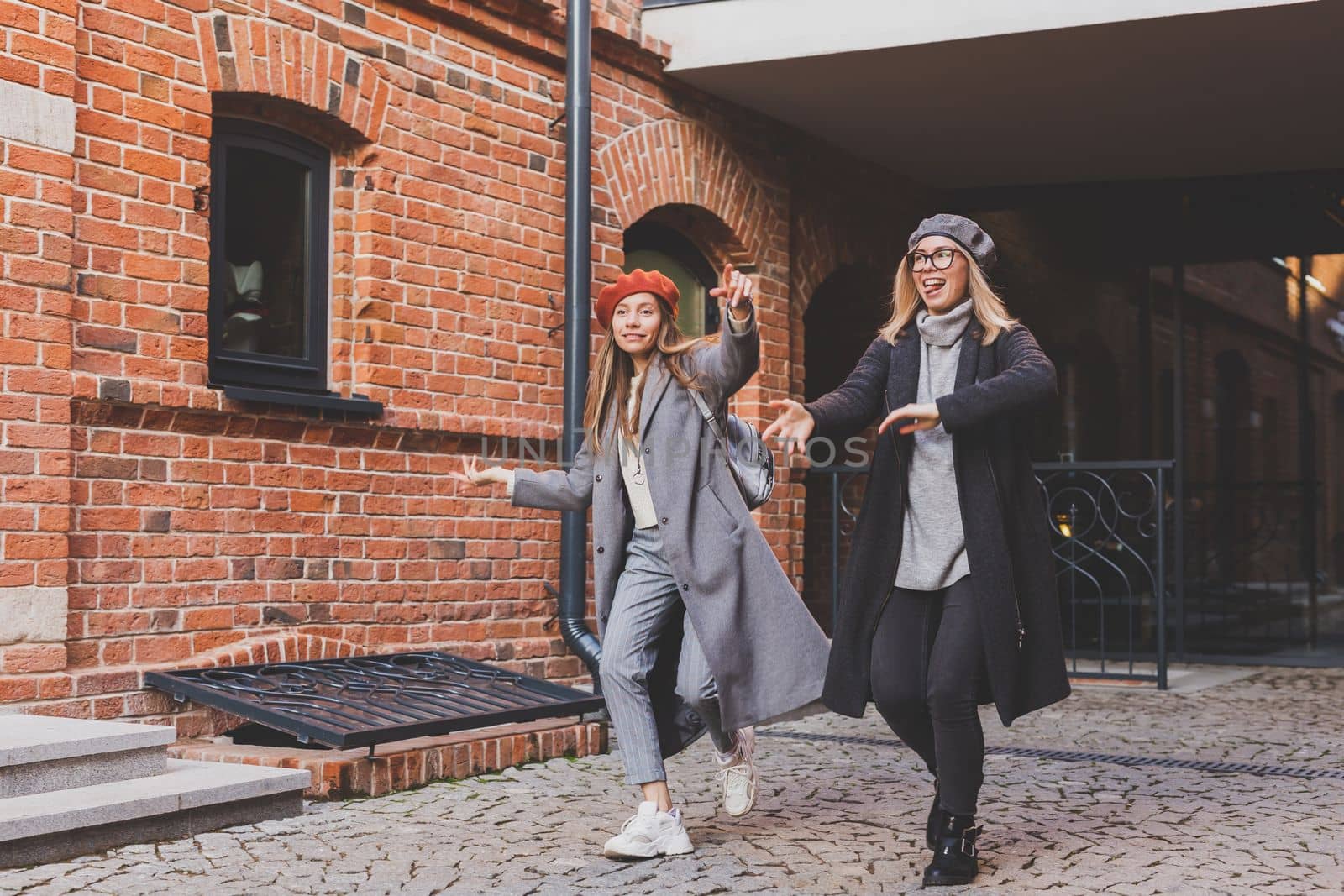 Young pretty girls friends having fun outdoor in autumn evening in city laughing and going crazy on the street - friendship and funny people