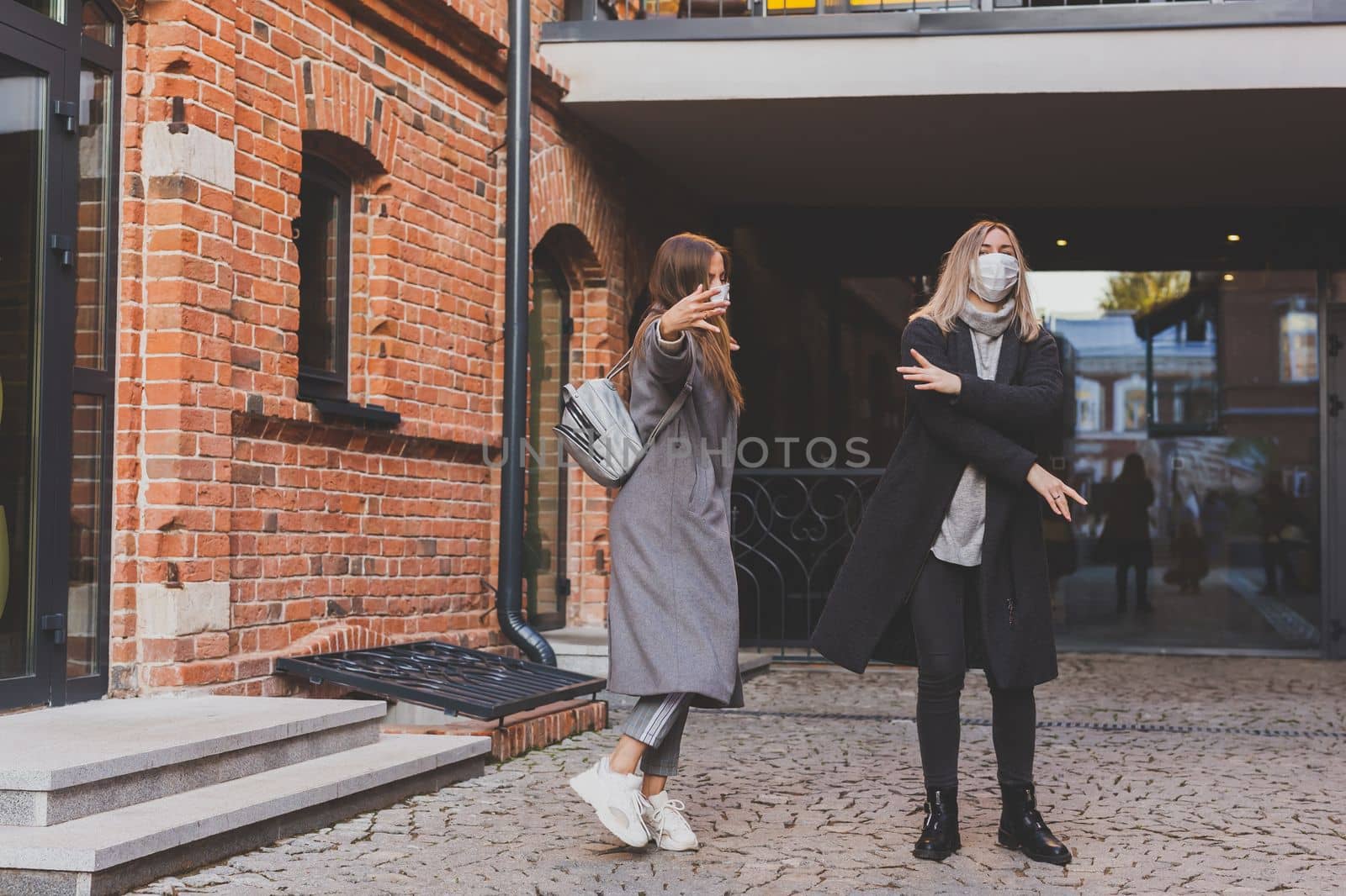 Young pretty girls friends having fun outdoor in autumn evening in city laughing and going crazy on the street - friendship and funny people