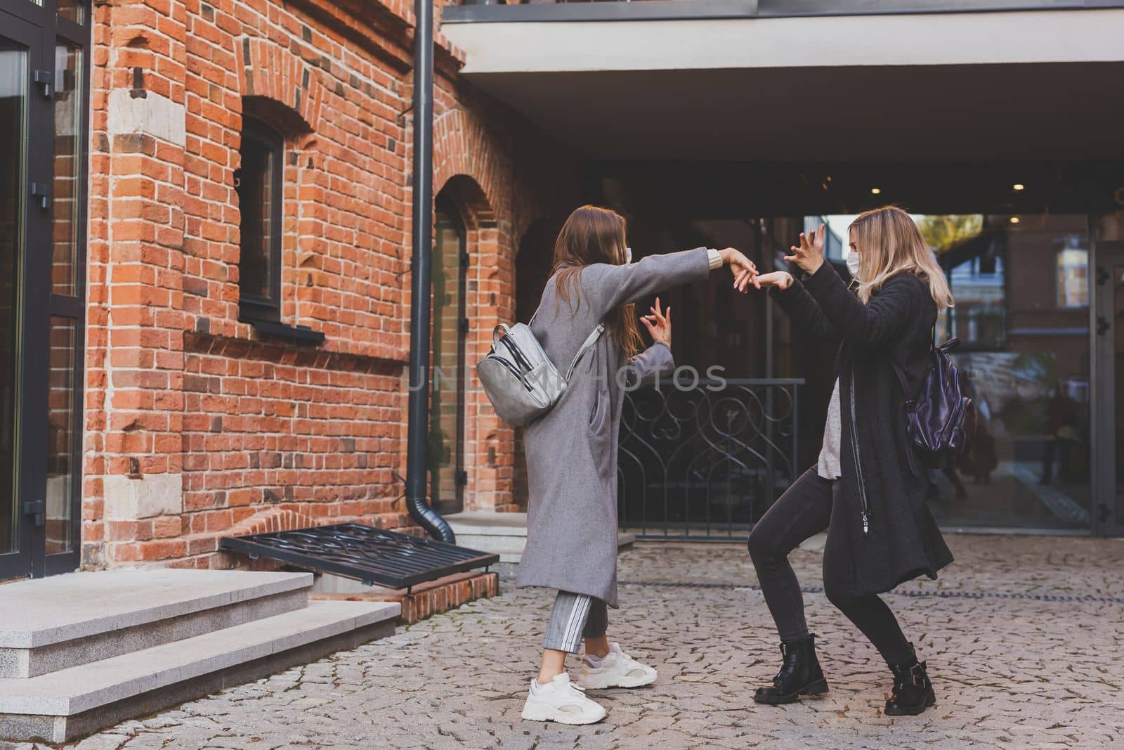 Young pretty girls friends having fun outdoor in autumn evening in city laughing and going crazy on the street - friendship and funny people