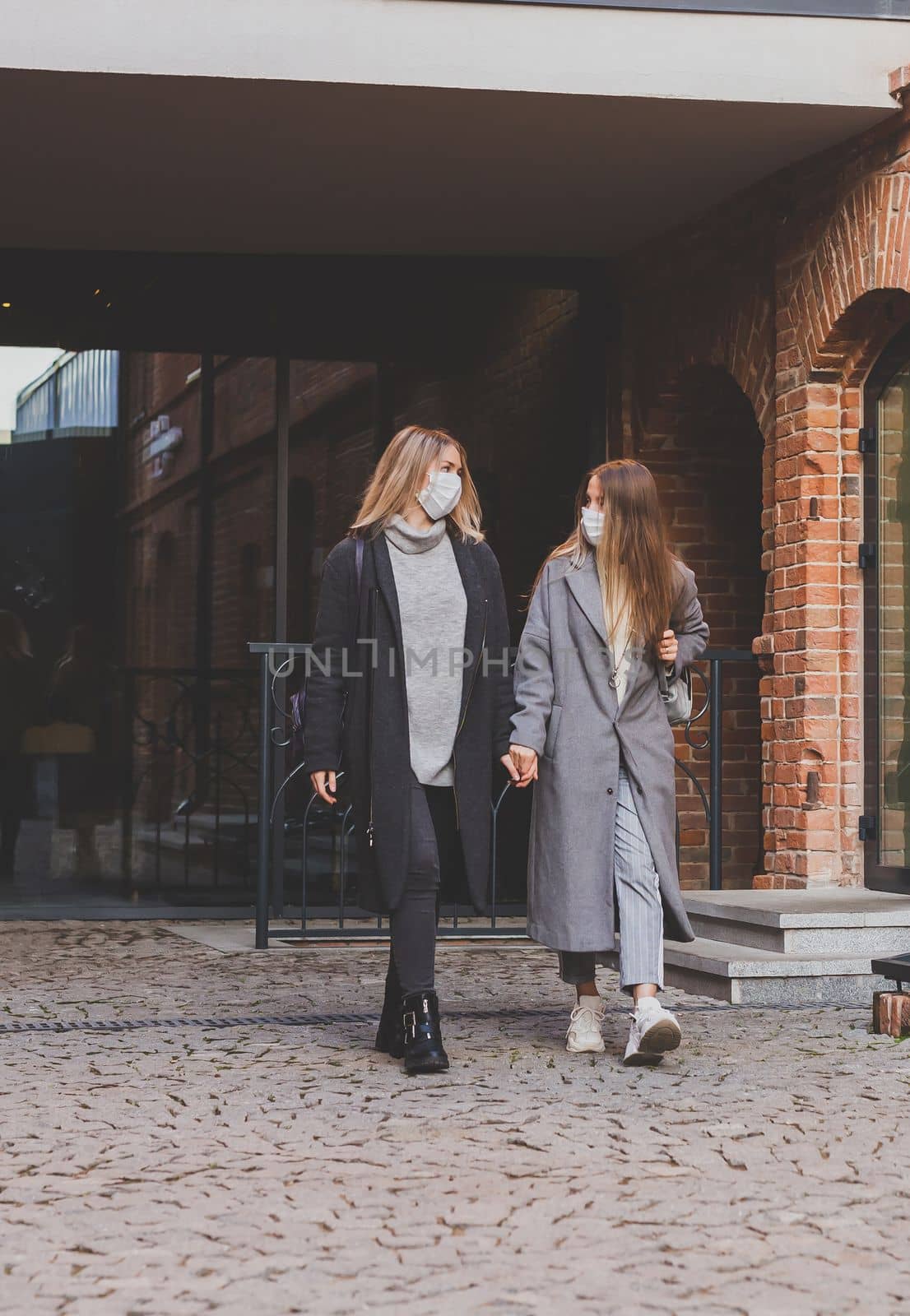 Young pretty girls friends having fun outdoor in autumn evening in city laughing and going crazy on the street - friendship and funny people