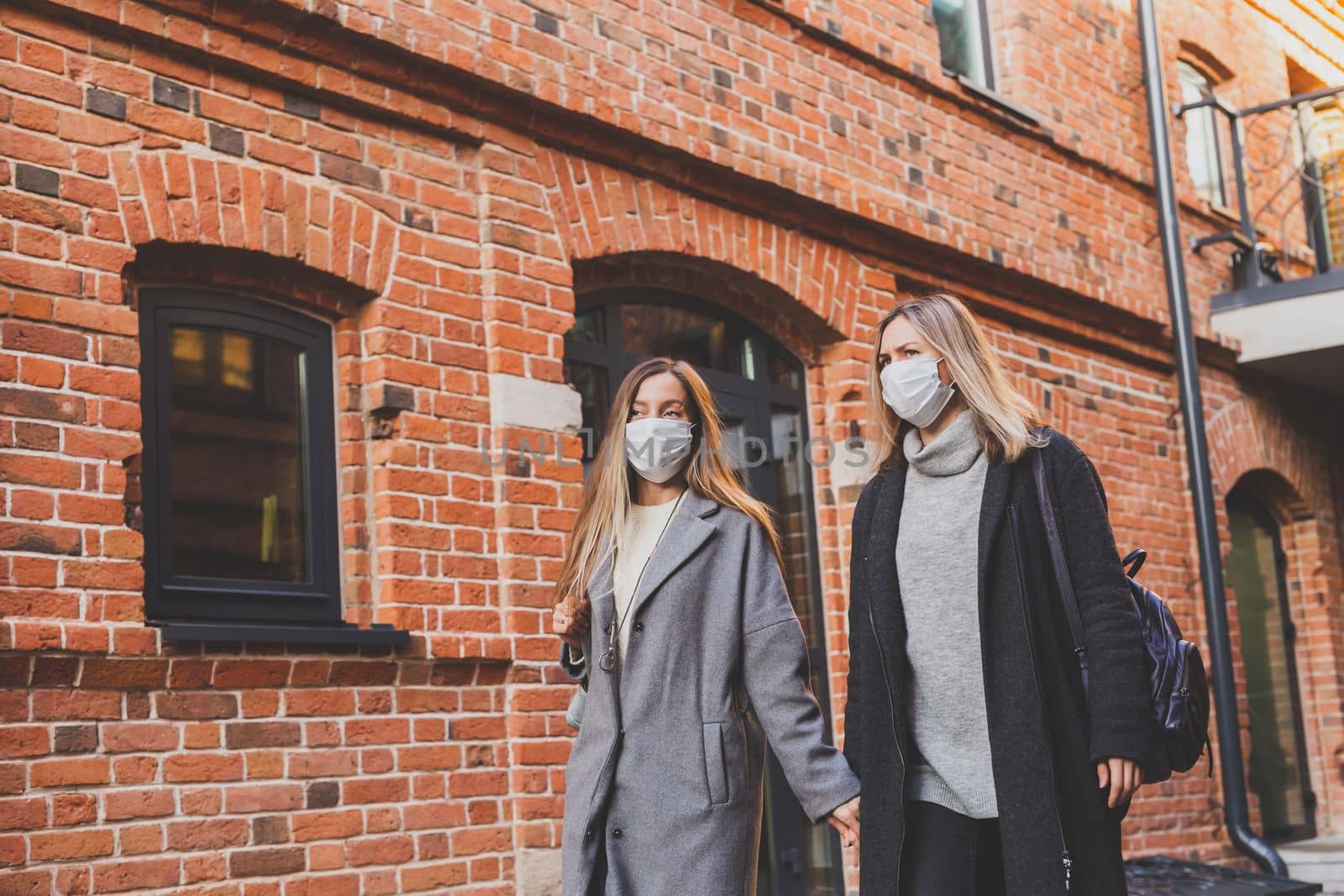 Young pretty girls friends in medical masks having fun outdoor in autumn evening in city laughing - end of pandemic concept by Satura86