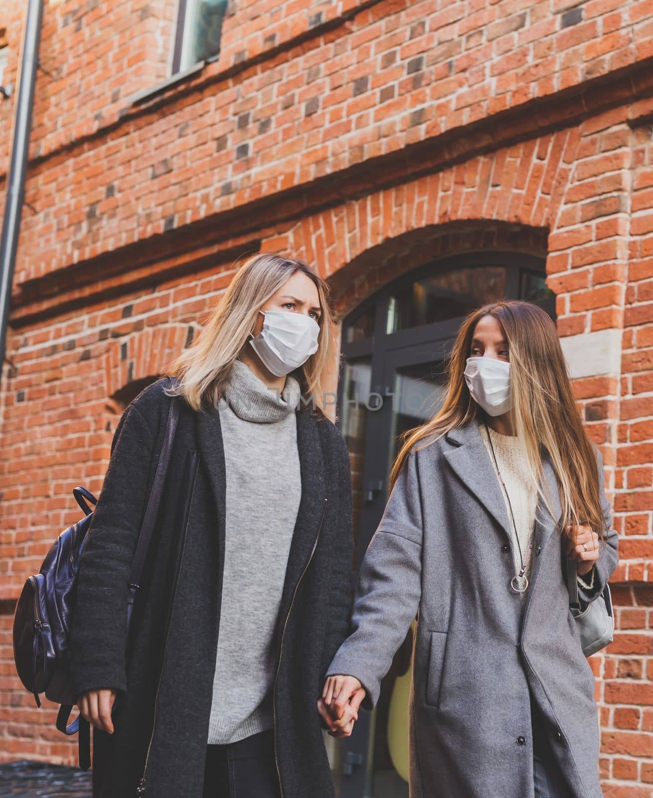Young pretty girls friends in medical masks having fun outdoor in autumn evening in city laughing - end of pandemic concept by Satura86