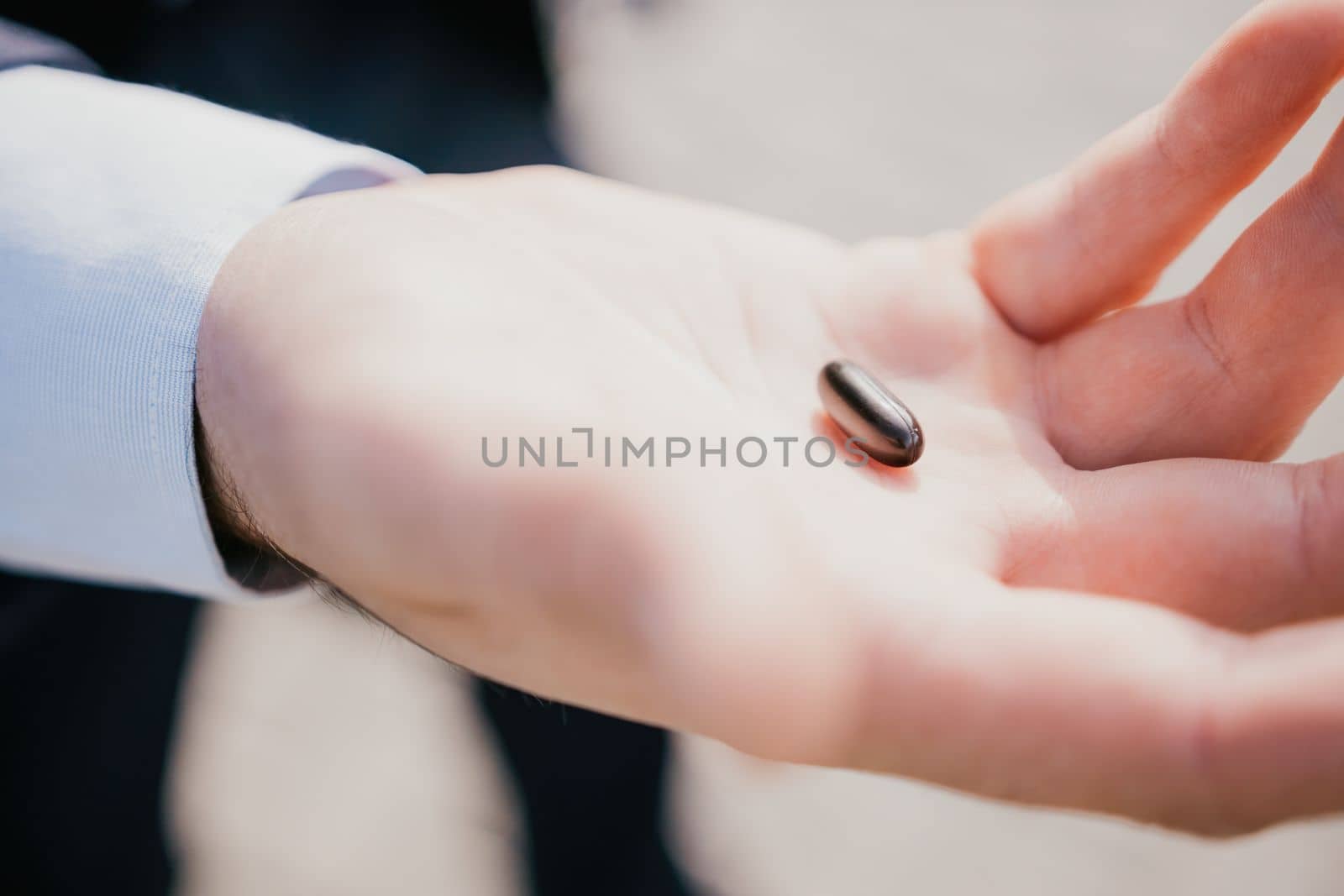 Man takes and shows pills vitamins or drugs tablets in hand from pill bottle, macro shot