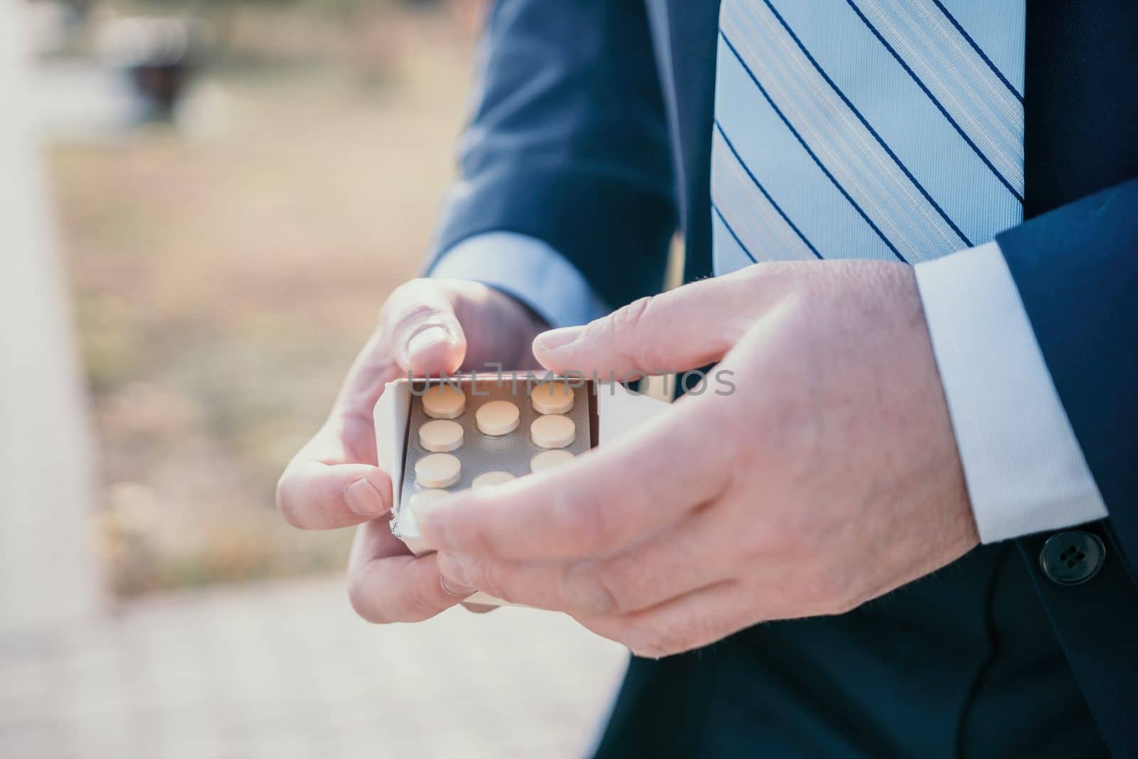 Man takes and shows pills vitamins or drugs tablets in hand from pill bottle, macro shot