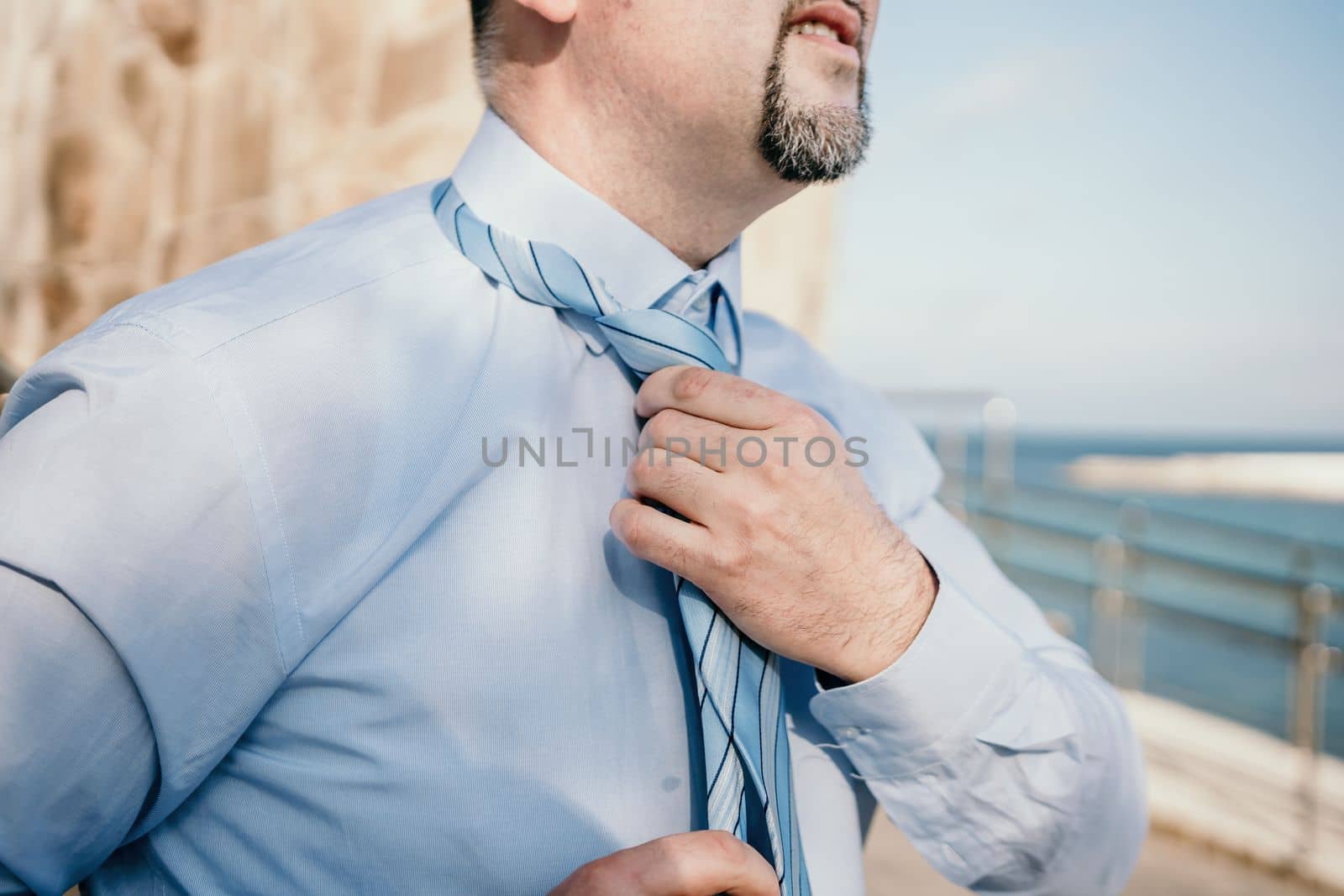 Close up of Man Adjusting Tie of Suit. Businessman in white shirt straightens his tie, close-up.