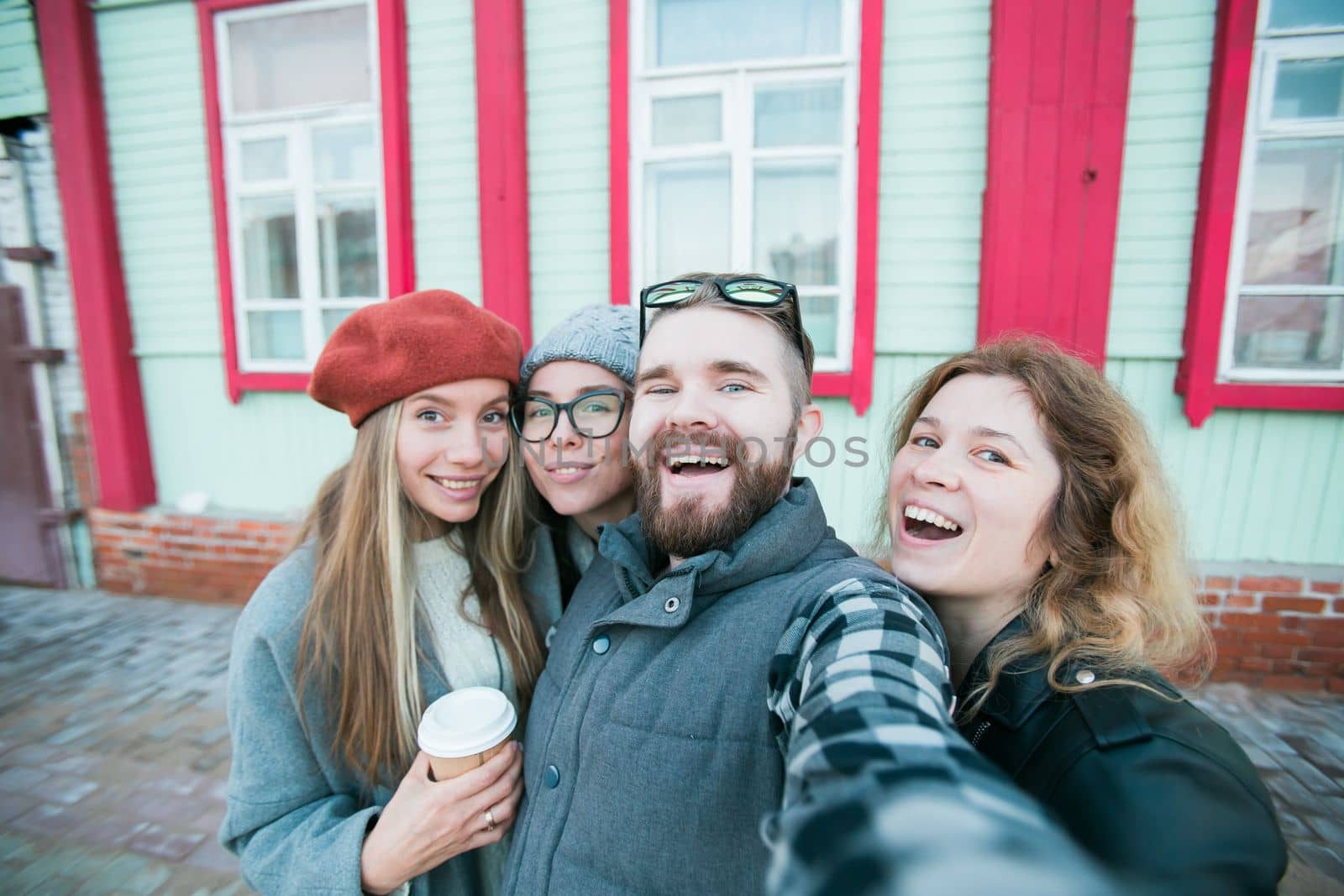 Group of happy young friends having fun on city street and taking selfie - friendship and photographing