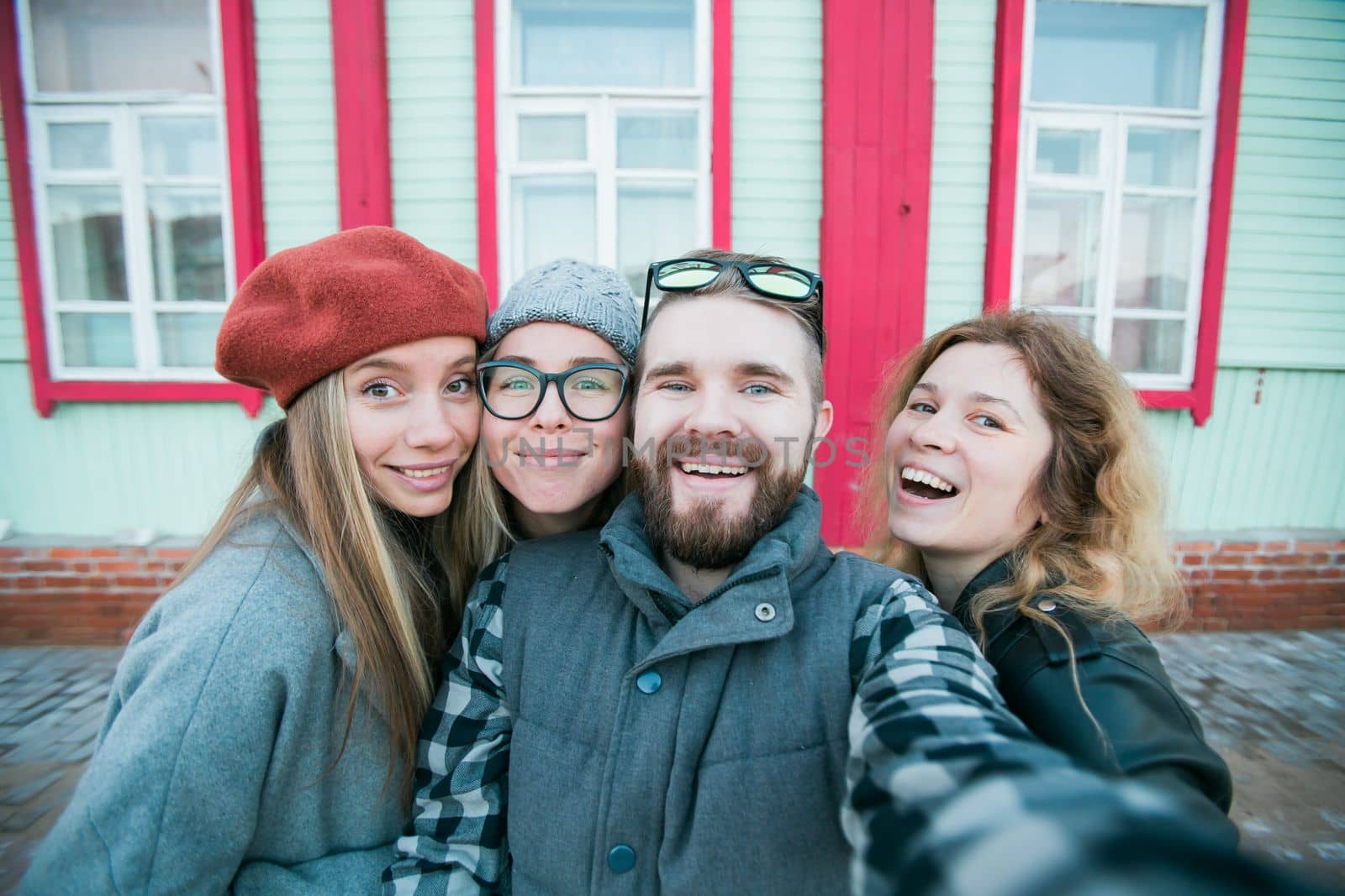 Group of happy young friends having fun on city street and taking selfie - friendship and photographing