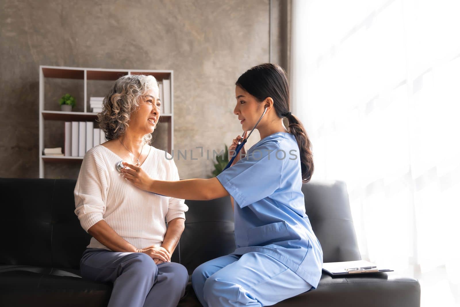 Stethoscope exam. Attractive cheerful asian female doctor listening to the elderly while using stethoscope.