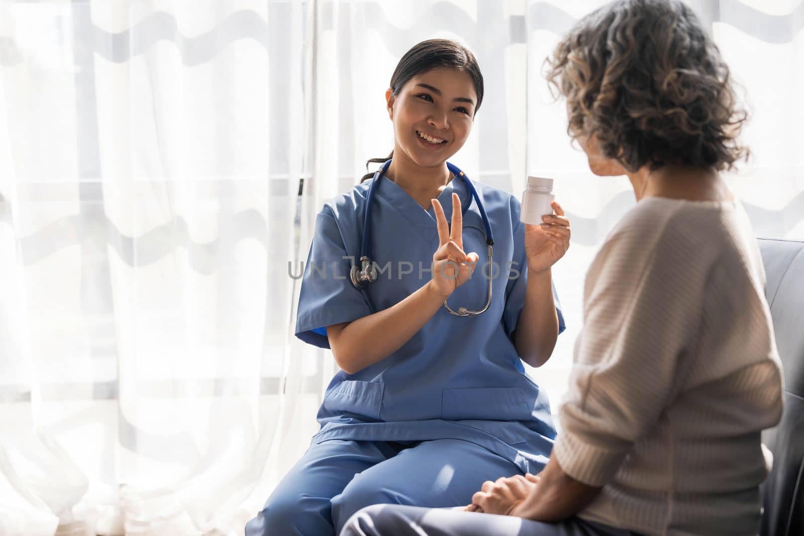 Healthcare worker or nurse caregiver giving pills, showing a prescription drug to senior woman. Elderly healthcare concept..