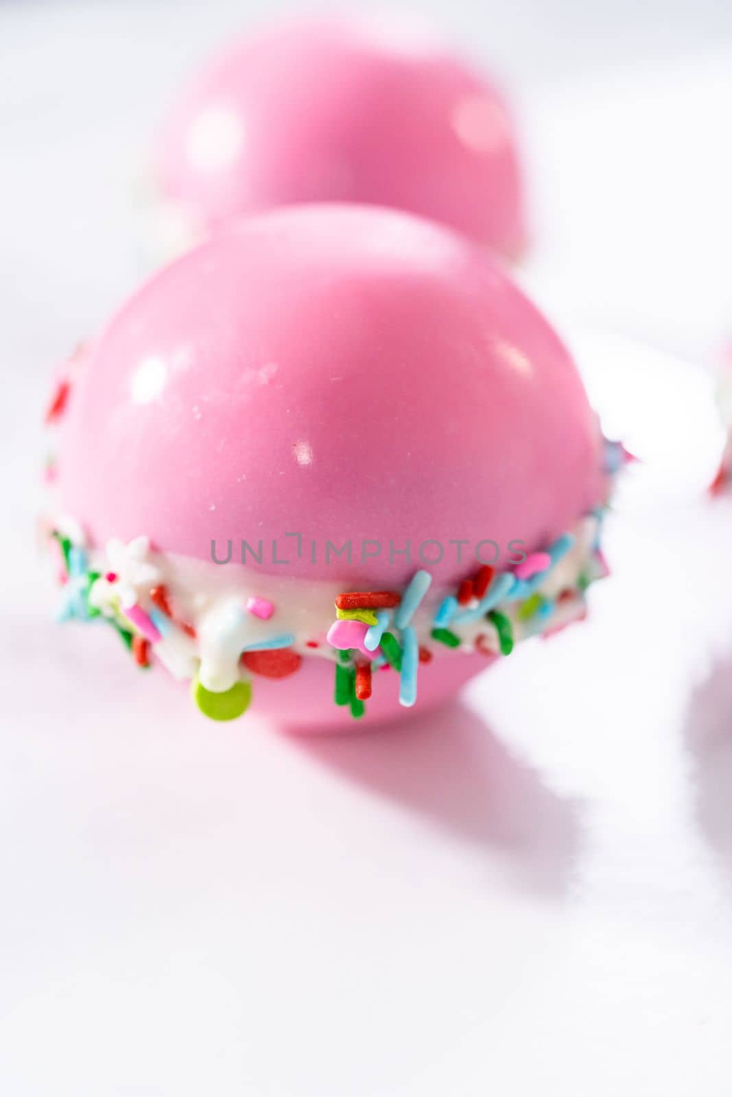 Drizzling melted chocolate on top of hot chocolate bombs.