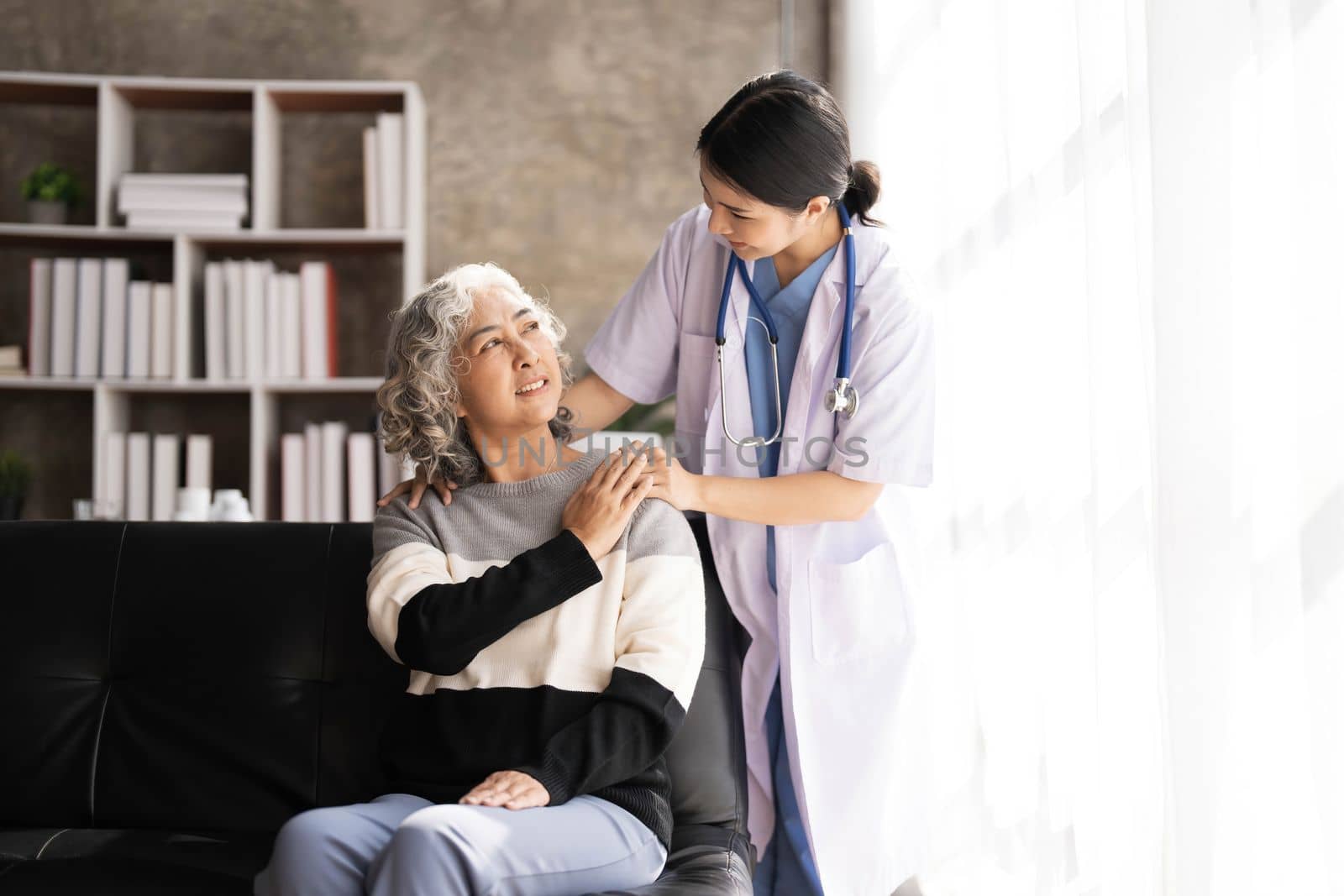 Young caregiver helping senior woman walking. Nurse assisting her old woman patient at nursing home. Senior woman with walking stick being helped by nurse at home...