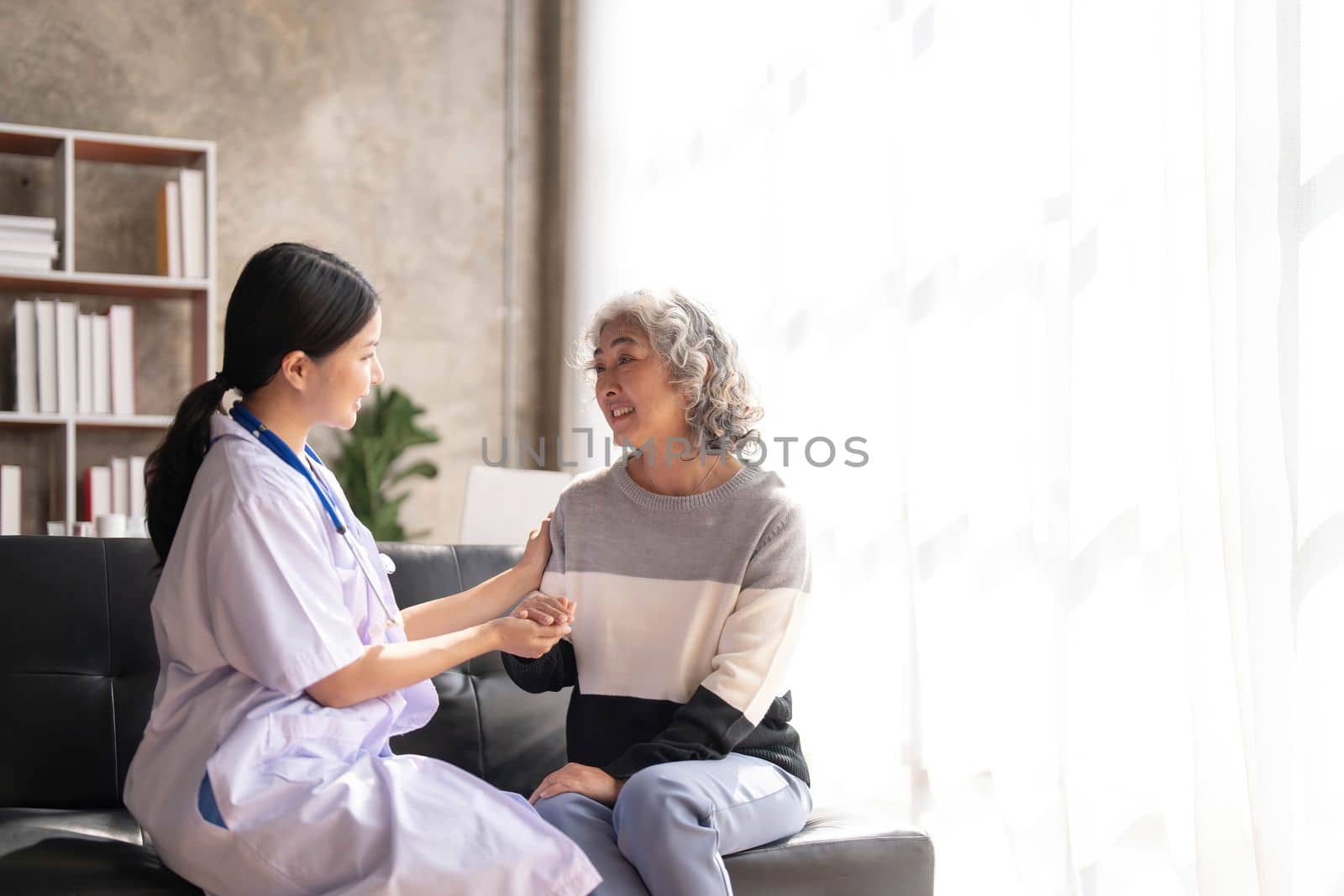 Young caregiver helping senior woman walking. Nurse assisting her old woman patient at nursing home. Senior woman with walking stick being helped by nurse at home...