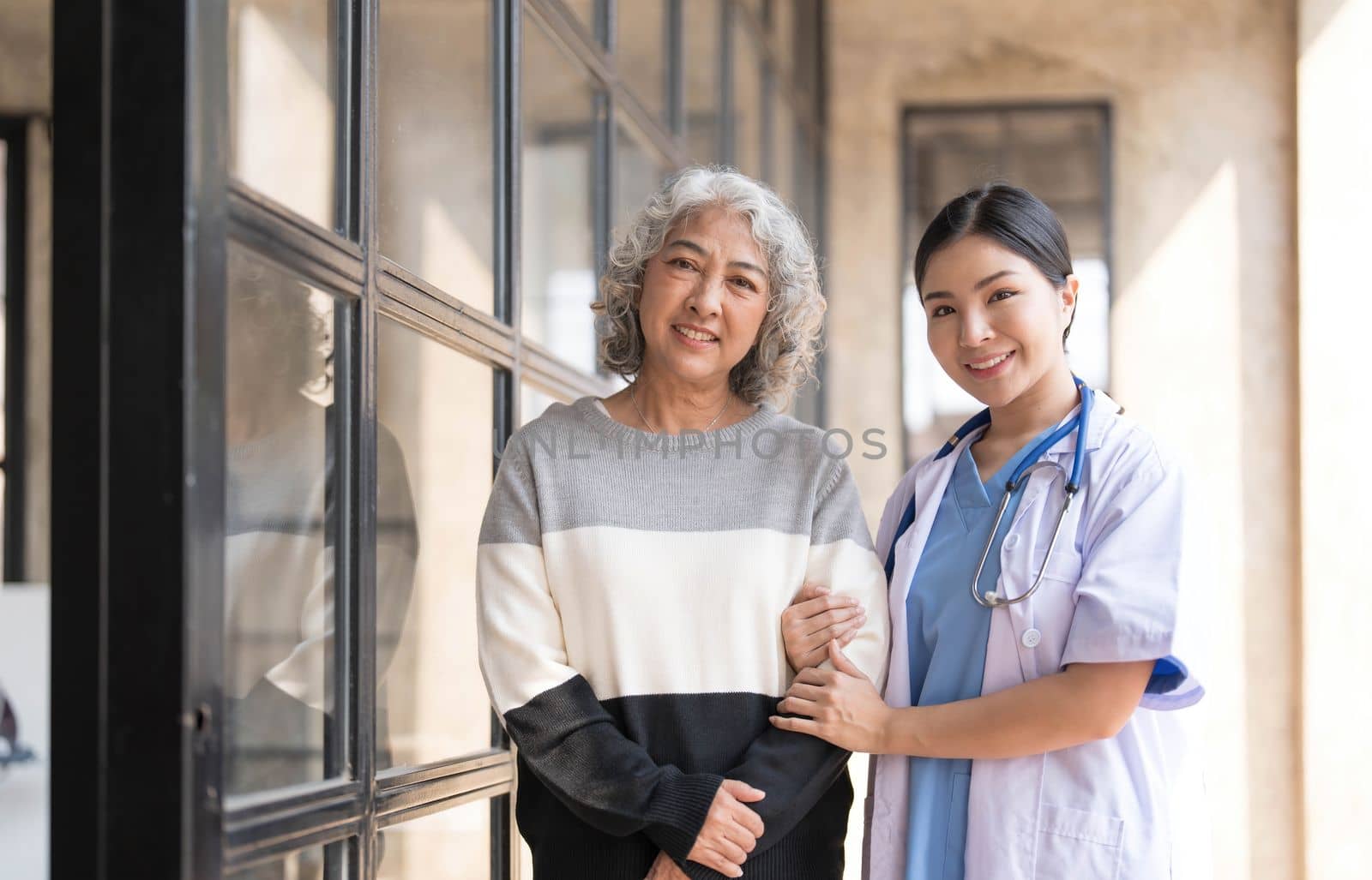 Young caregiver helping senior woman walking. Nurse assisting her old woman patient at nursing home. Senior woman with walking stick being helped by nurse at home...