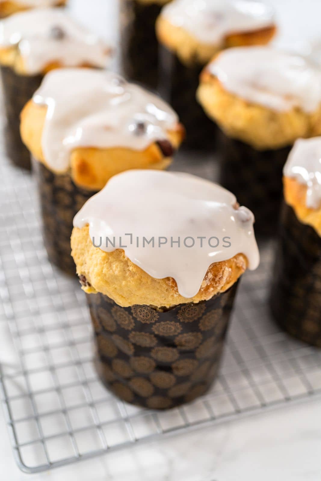 Glazing mini Easter bread kulich with a white lemon glaze.